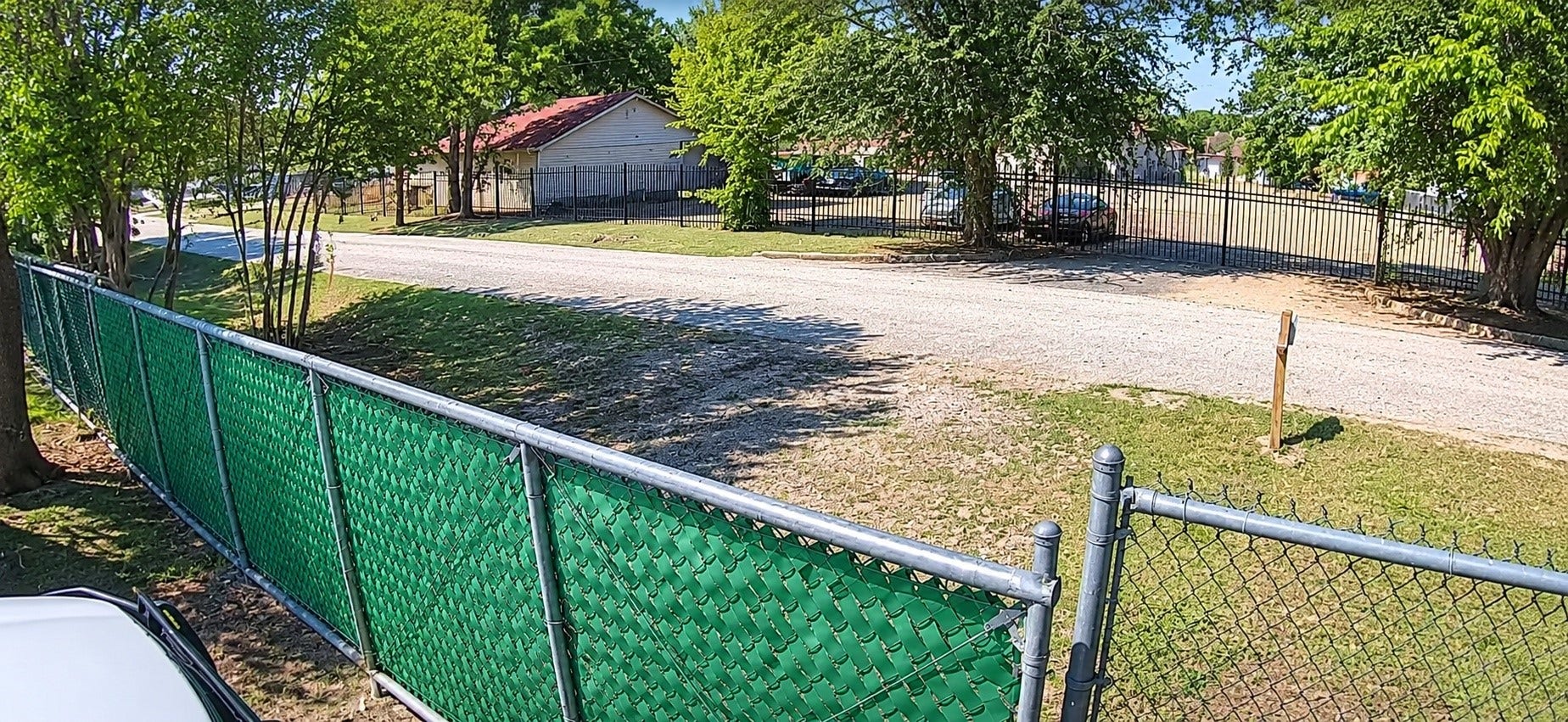 9410 Klondike Street, Houston, TX 77075 Gated and fenced property featuring a gravel driveway, mature trees, and open space.