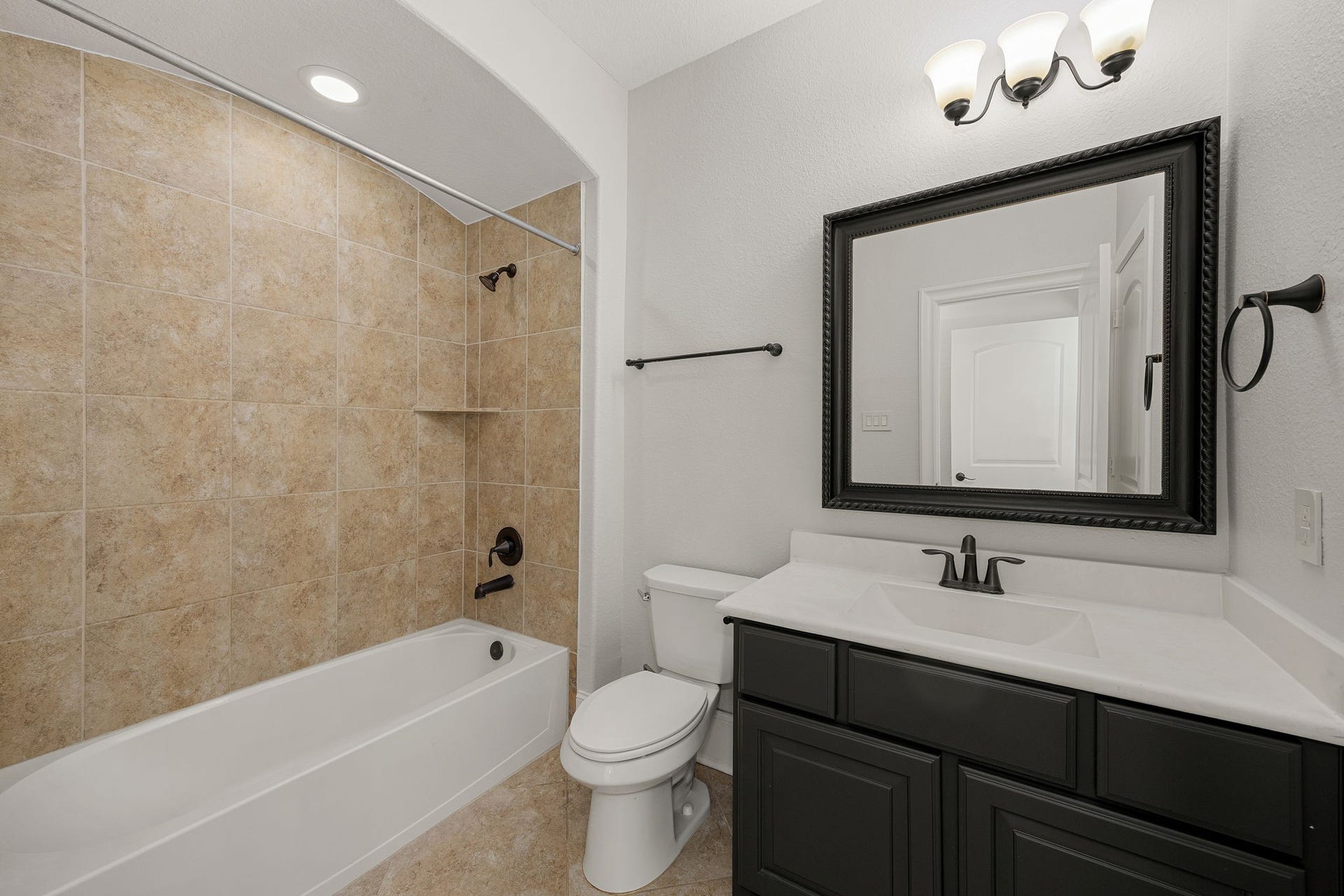 5127 Beekman Drive, Missouri City, TX 77459 This secondary bathroom offers a tub/shower combo framed in warm tile, complemented by an elegant vanity and designer lighting.