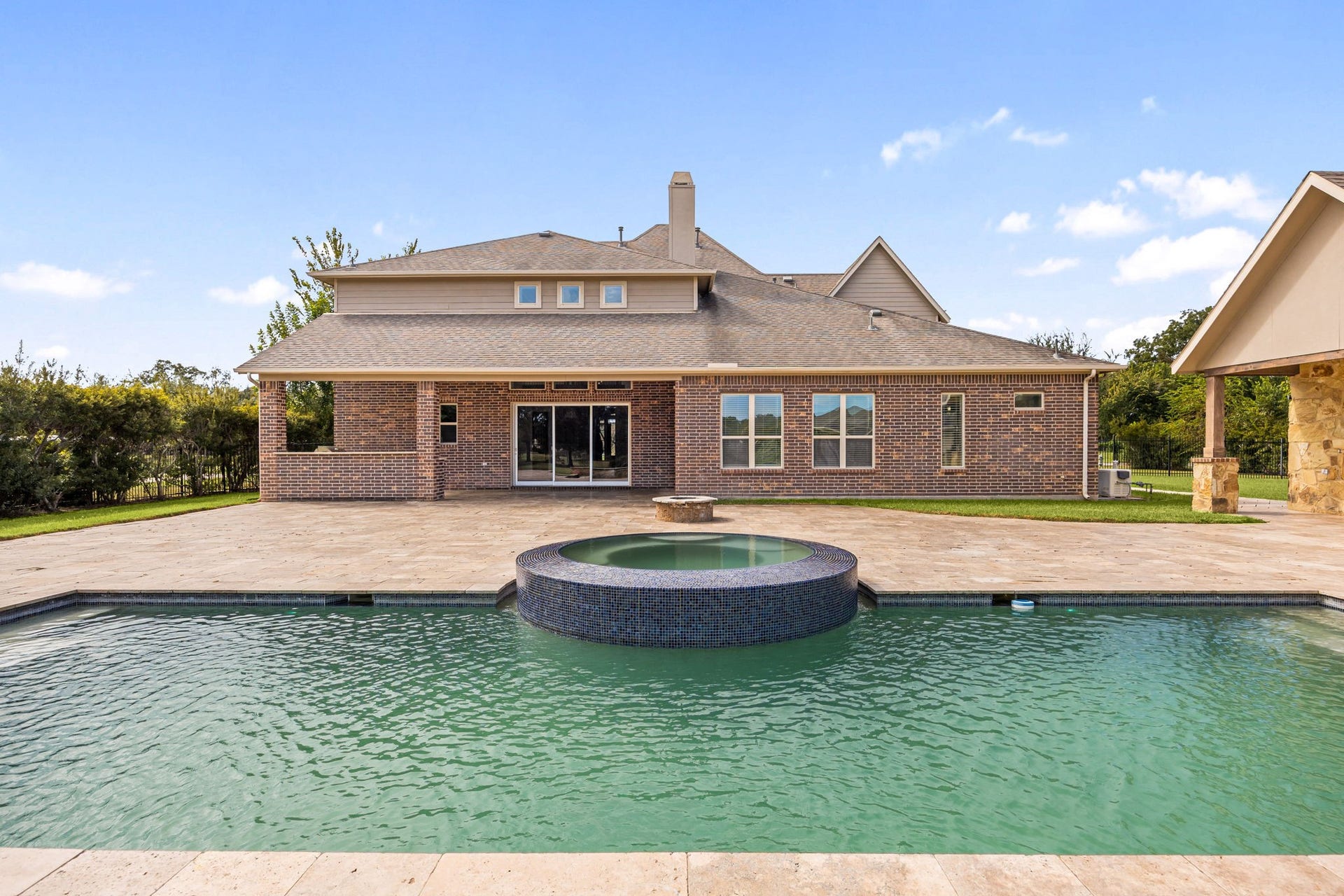 5127 Beekman Drive, Missouri City, TX 77459 The resort-style pool and spa offer a stunning centerpiece to the backyard, framed by elegant travertine decking and lush, manicured lawn.