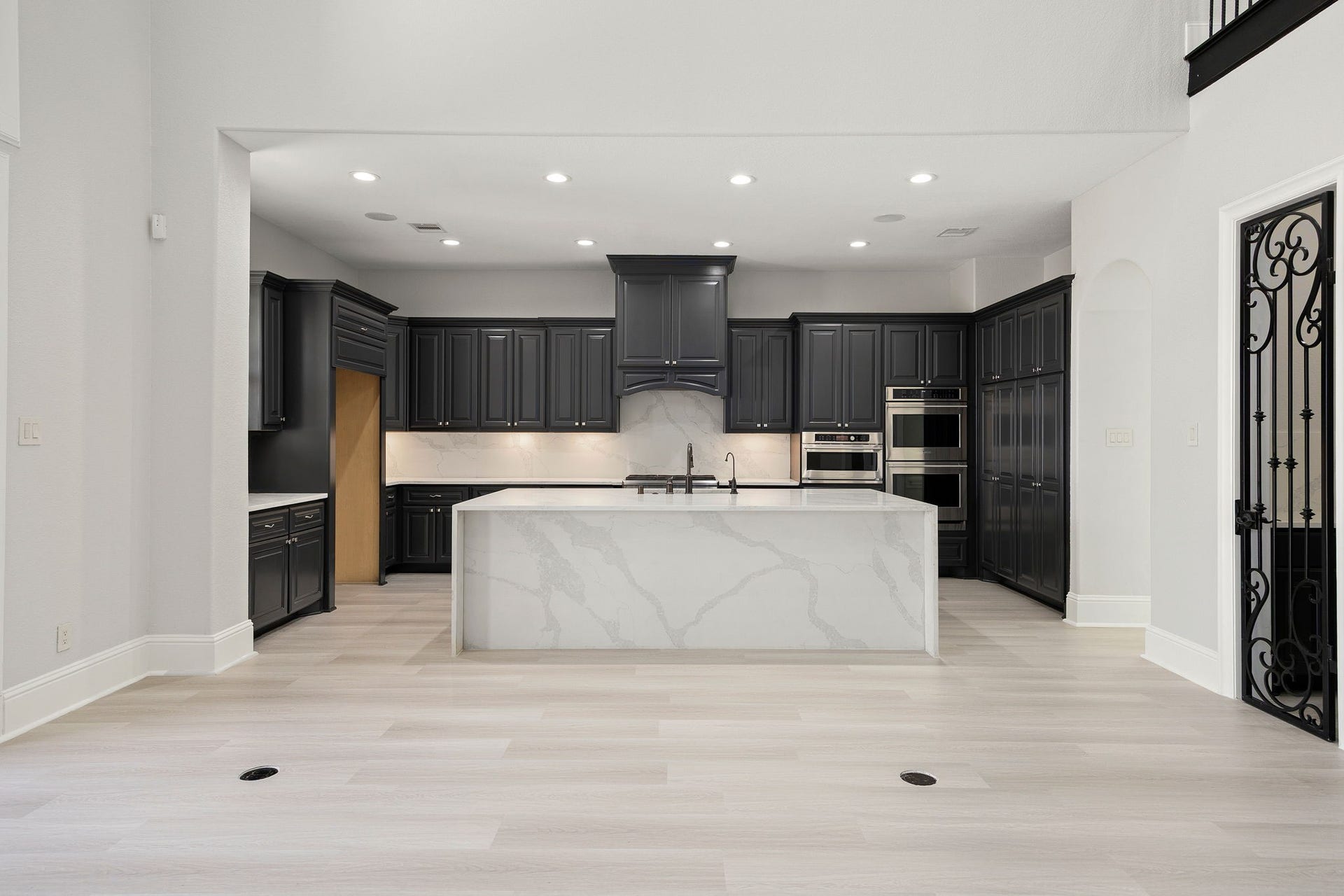 5127 Beekman Drive, Missouri City, TX 77459 This impressive kitchen features a large island with breakfast bar seating, sleek dark cabinetry, double ovens, and recessed lighting throughout.