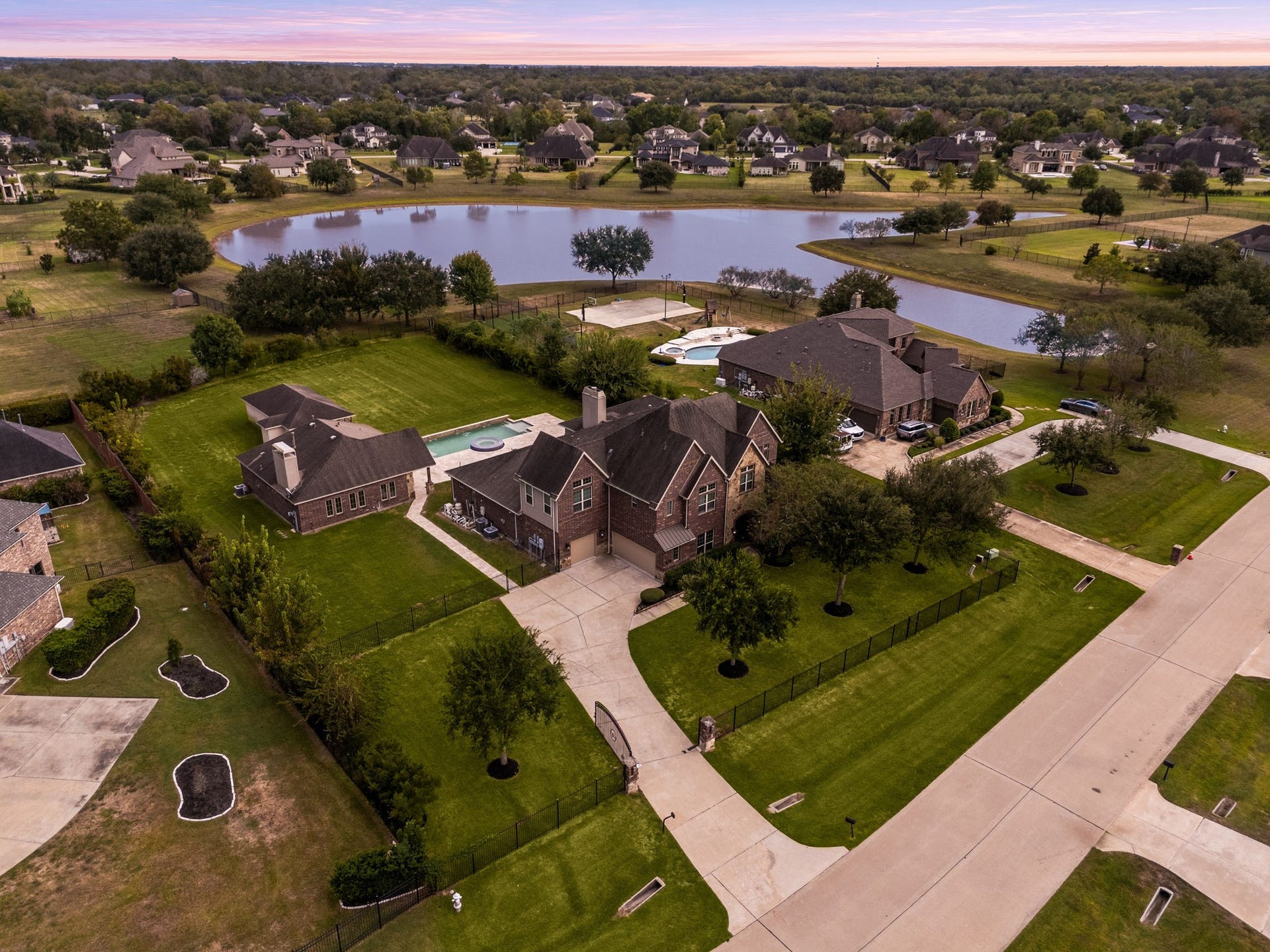 5127 Beekman Drive, Missouri City, TX 77459 This twilight aerial view captures the full scope of the estate, the main residence, detached casita, and resort-style pool all set against the backdrop of the private, acre-plus lot and surrounding community.