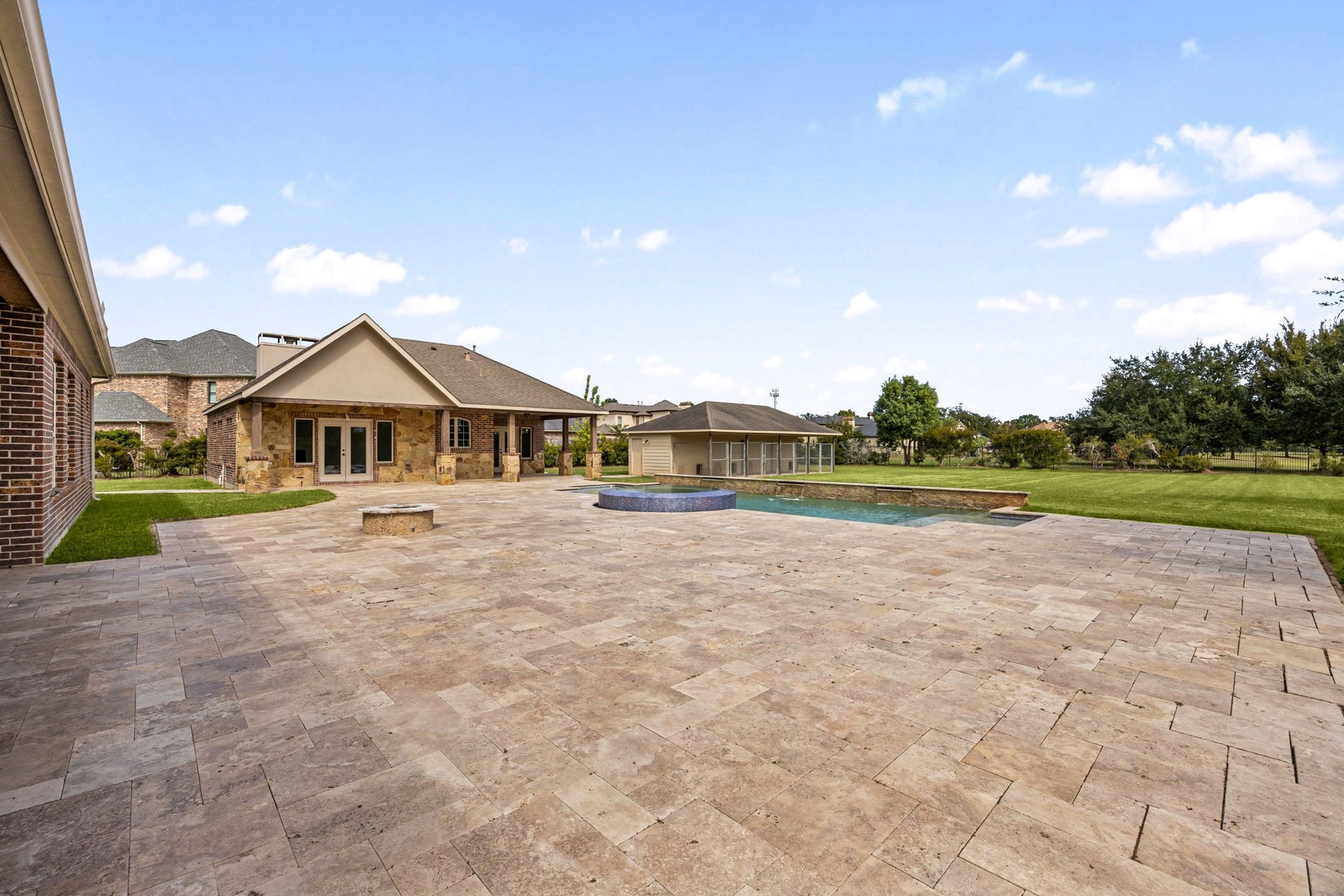 5127 Beekman Drive, Missouri City, TX 77459 The expansive backyard unfolds across the propertys acre-plus lot, anchored by a sprawling travertine patio, a stone firepit, and the sparkling pool beyond, an entertainers paradise from every angle.