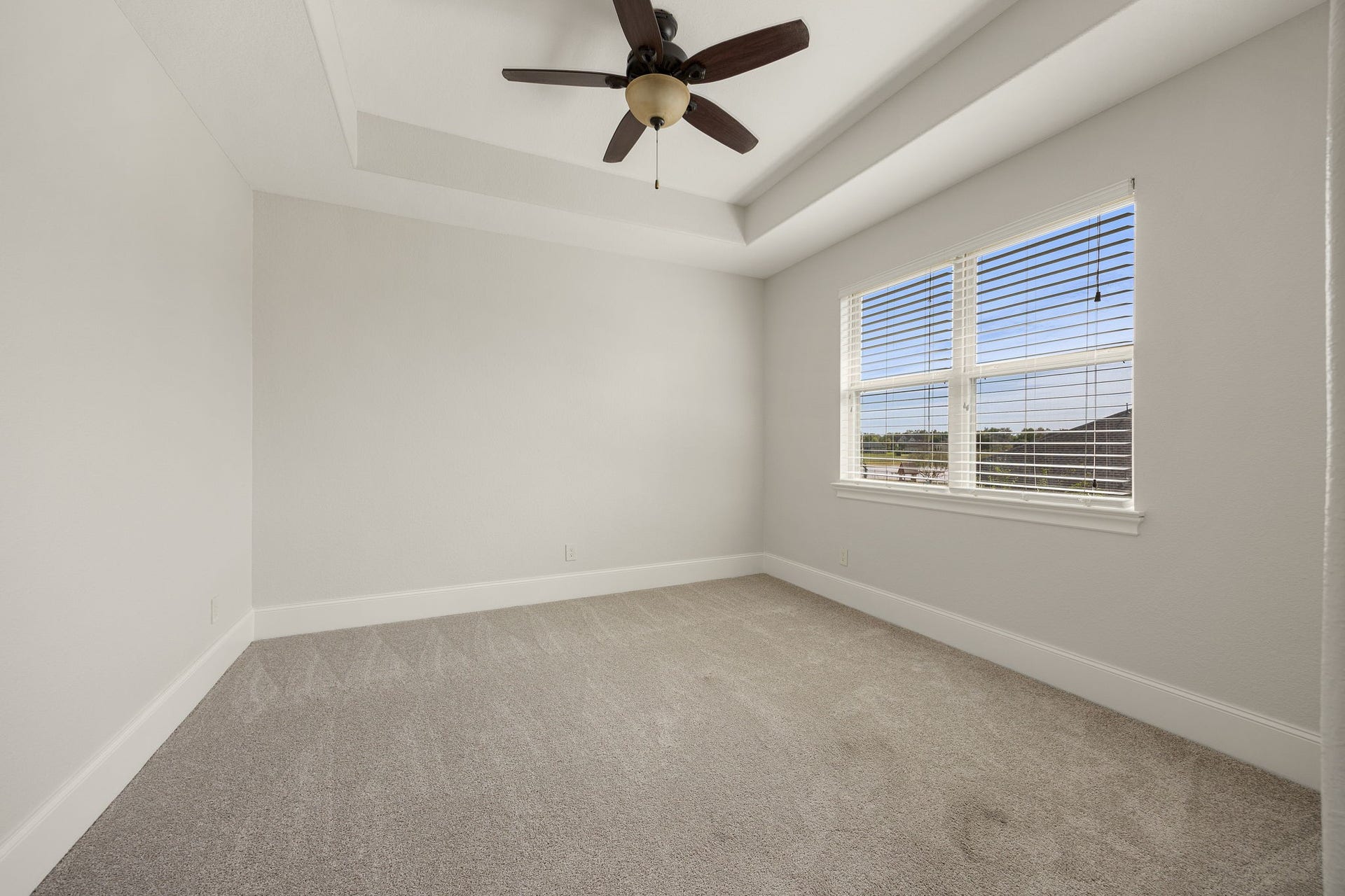 5127 Beekman Drive, Missouri City, TX 77459 A beautifully proportioned secondary bedroom features a tray ceiling, ceiling fan, and generous windows overlooking the grounds below.