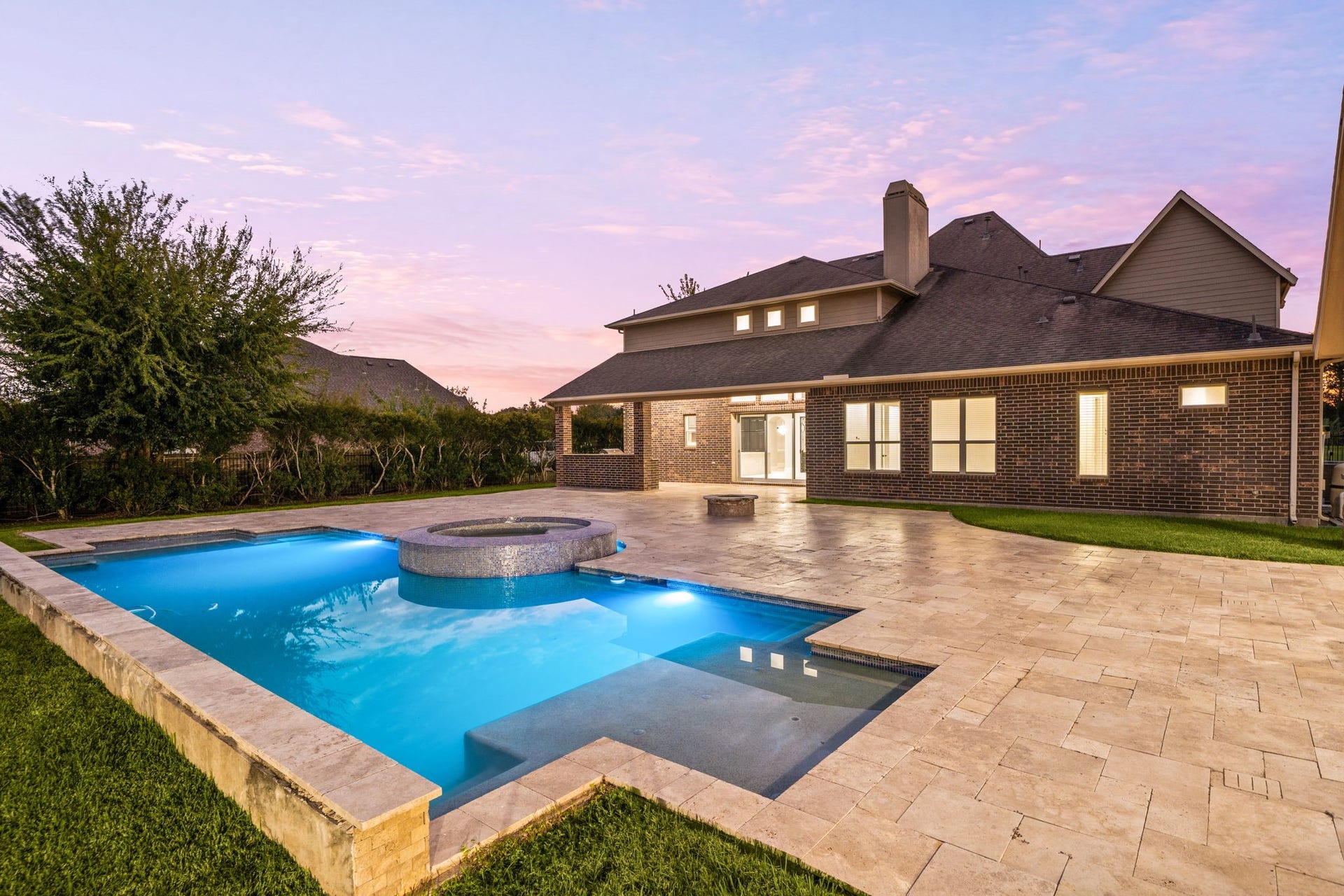 5127 Beekman Drive, Missouri City, TX 77459 As evening falls, the pool and spa glow beautifully against the illuminated home, creating a resort-like ambiance perfect for entertaining.