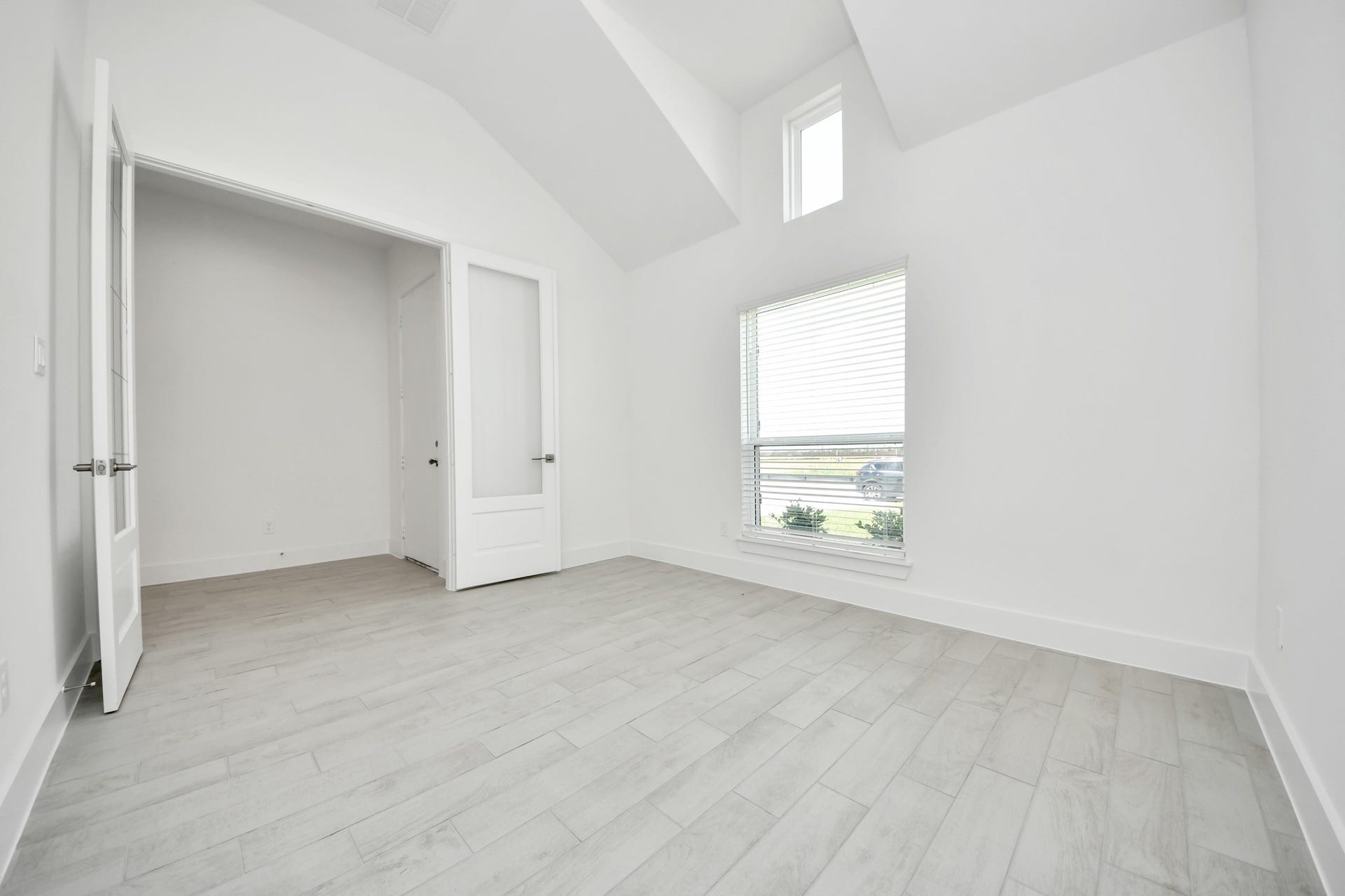 Experience the perfect blend of sophistication and warmth in this home office, boasting elegant wood-look tile flooring and flooded with natural light from expansive windows and French doors. Sample photo of completed home with similar floor plan. Actual colors and selections may vary.