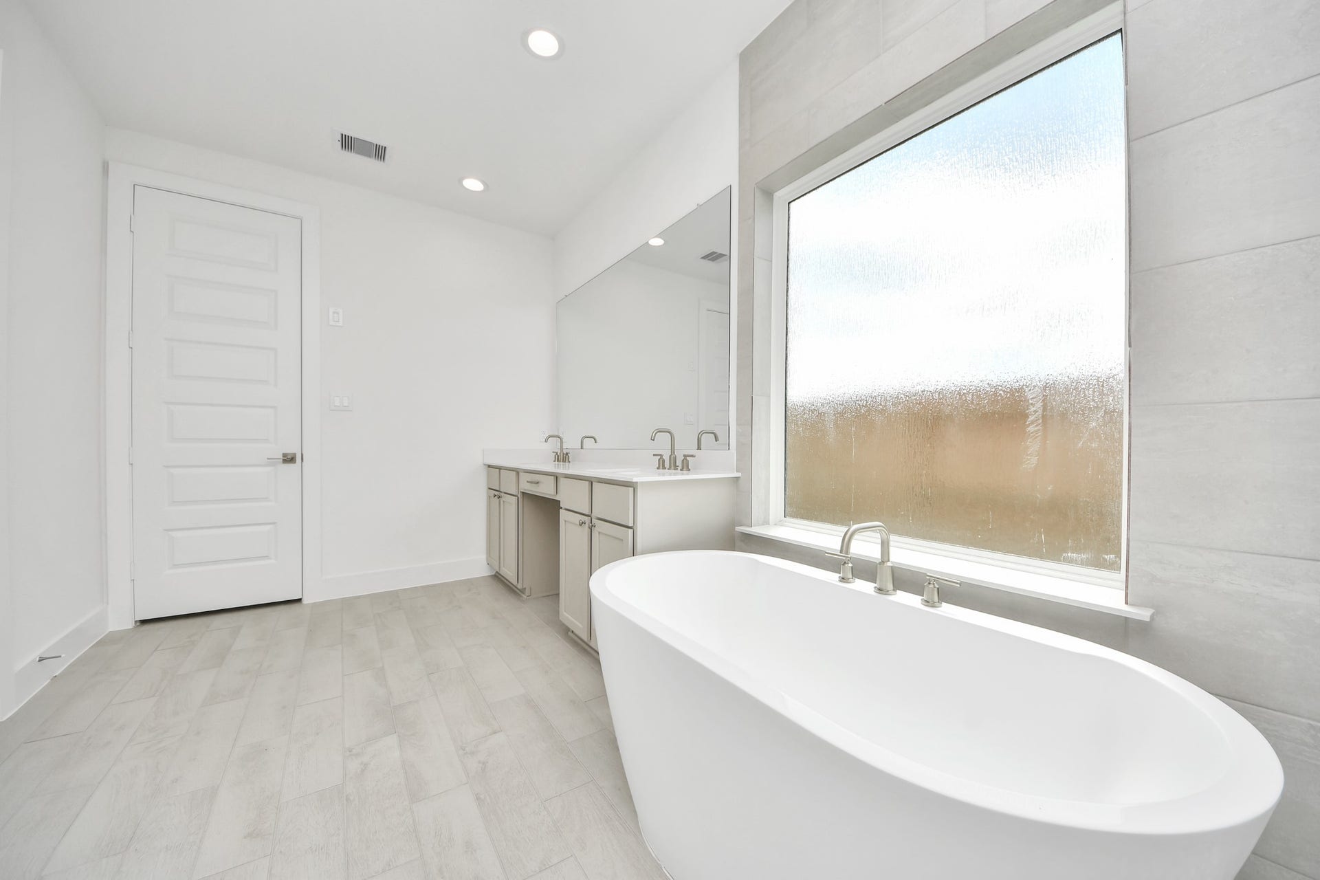 Indulge in a spa-like retreat within the confines of this primary bathroom. Delight in a spacious walk-in shower enveloped in stylish tile surround, unwind in a separate garden tub adorned with custom detailing. Sample photo of completed home with similar floor plan. Actual colors and selections may vary.