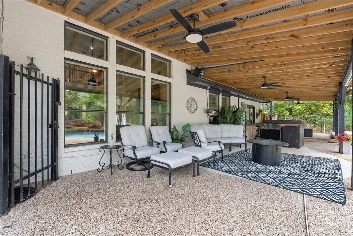 7202 Pine Drive W, Alvin, TX 77511 Spacious covered patio with stylish seating, ceiling fans, and a cozy fire pit, perfect for outdoor entertaining and relaxation.