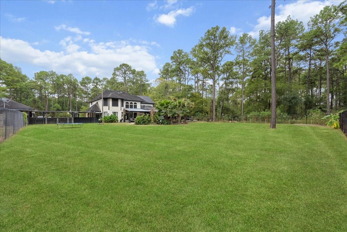7202 Pine Drive W, Alvin, TX 77511 Expansive backyard with lush green lawn, surrounded by mature trees, offering privacy and a picturesque view of the two-story home.
