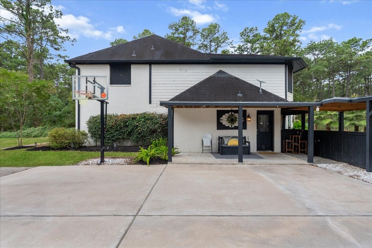 7202 Pine Drive W, Alvin, TX 77511 Charming two-story home with a welcoming covered patio, nestled amidst lush greenery. The spacious driveway and basketball hoop add a touch of leisure to this serene property.