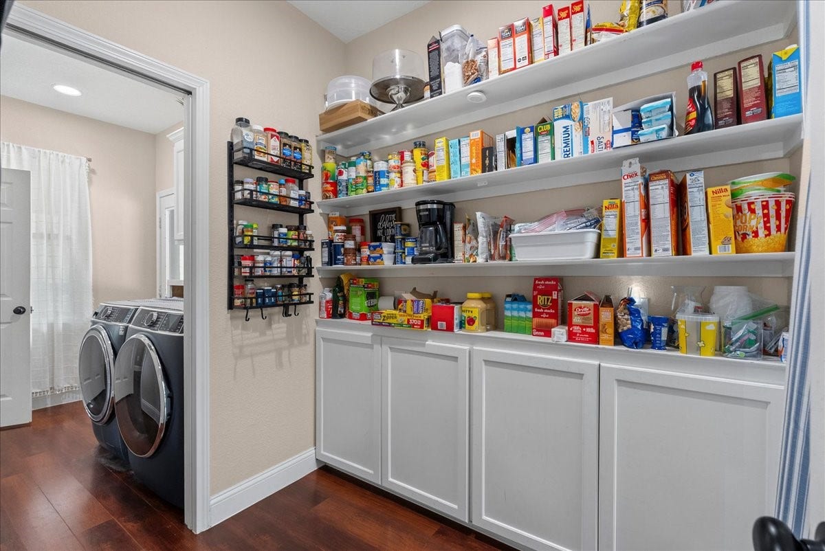 7202 Pine Drive W, Alvin, TX 77511 Spacious pantry with ample shelving for organized storage, adjacent to a modern laundry area with sleek appliances and hardwood like flooring.