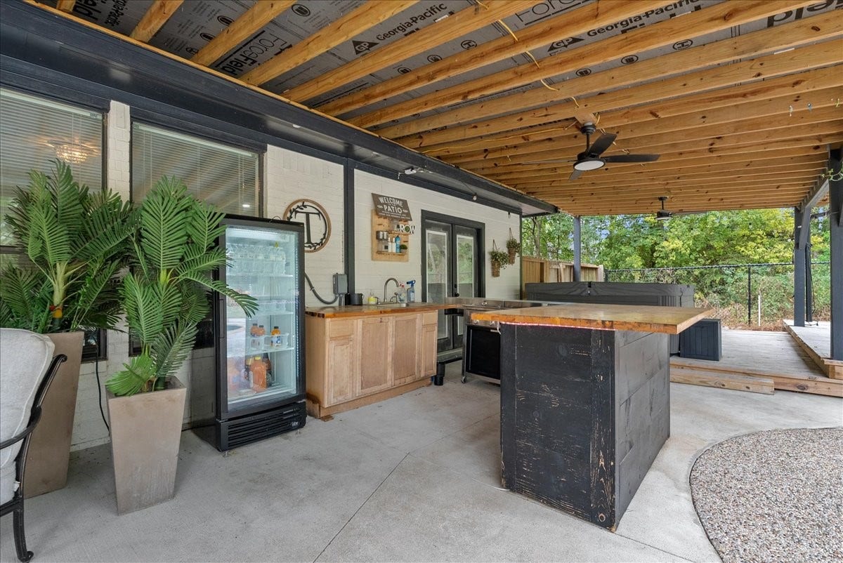 7202 Pine Drive W, Alvin, TX 77511 Spacious covered patio featuring a modern outdoor kitchen with a sleek bar, mini-fridge, and hot tub, perfect for entertaining and relaxation.