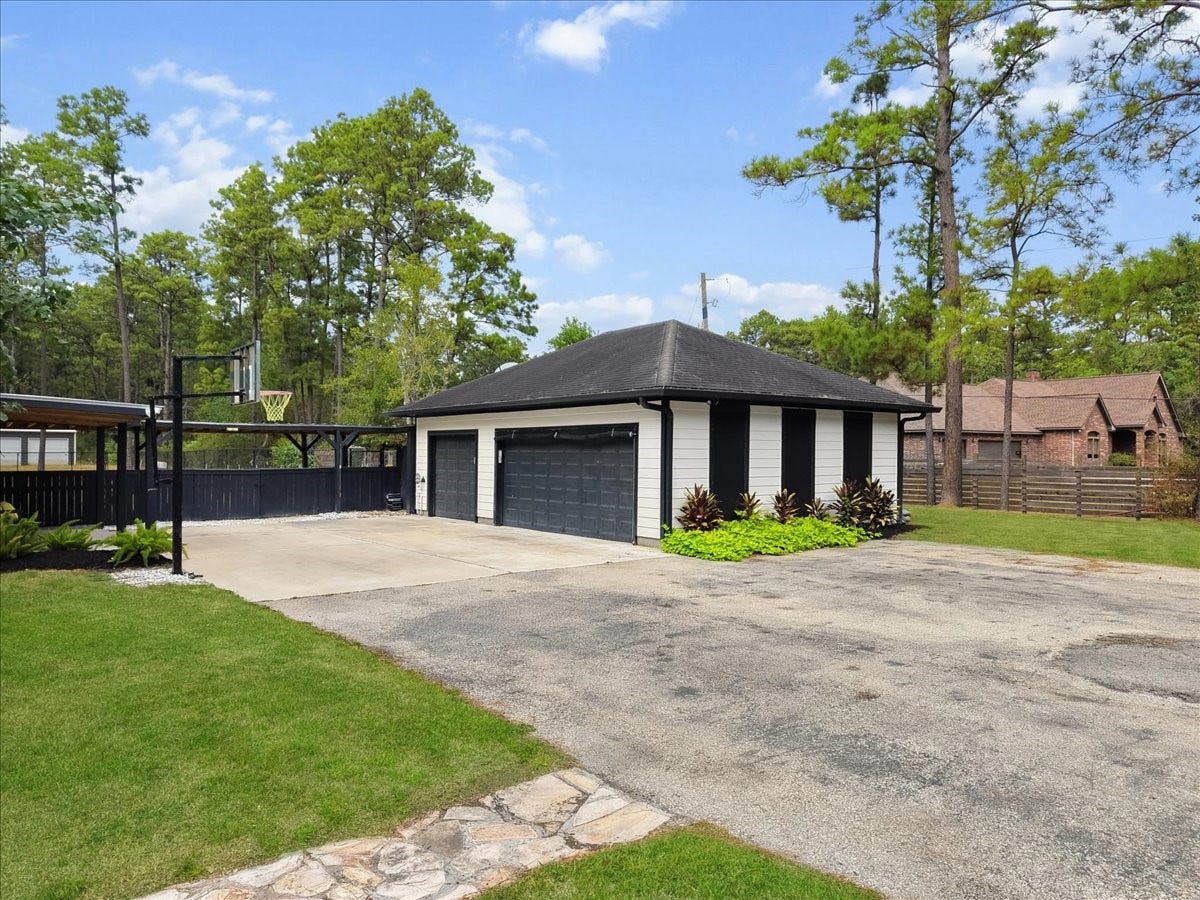 7202 Pine Drive W, Alvin, TX 77511 Spacious driveway leads to a modern three-car garage, surrounded by lush greenery and tall trees, offering ample parking and privacy. Garage is also engineered to ad upstairs garage apartment.