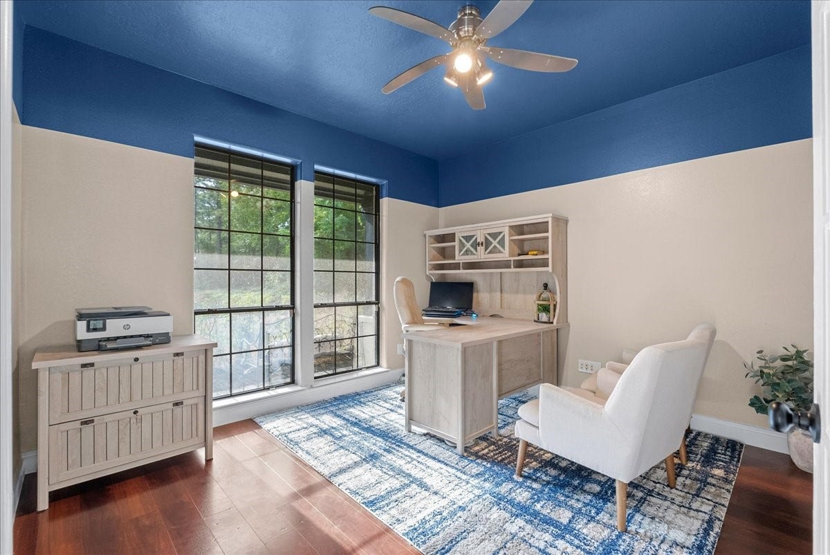 7202 Pine Drive W, Alvin, TX 77511 Bright home office with large windows, modern ceiling fan, and stylish furniture, offering a productive and comfortable workspace.