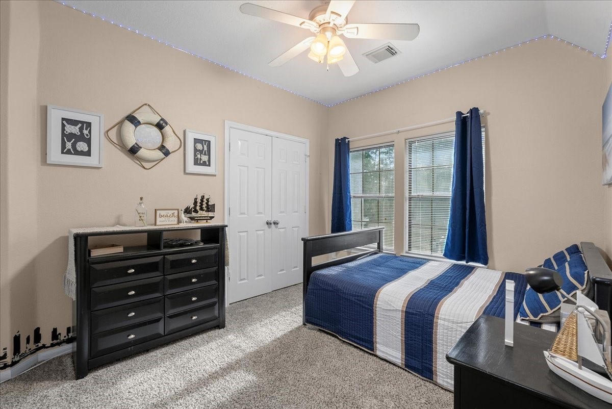 7202 Pine Drive W, Alvin, TX 77511 Charming bedroom with nautical decor features a cozy bed, ample natural light from large windows, and a spacious closet, creating a relaxing retreat.