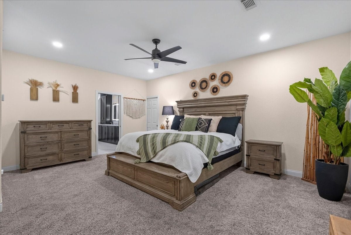 7202 Pine Drive W, Alvin, TX 77511 Spacious primary bedroom with a plush carpet, featuring a stylish wooden bed frame and matching dresser. The room is accented by modern wall decor, a ceiling fan, and abundant natural light, creating a cozy and inviting atmosphere.