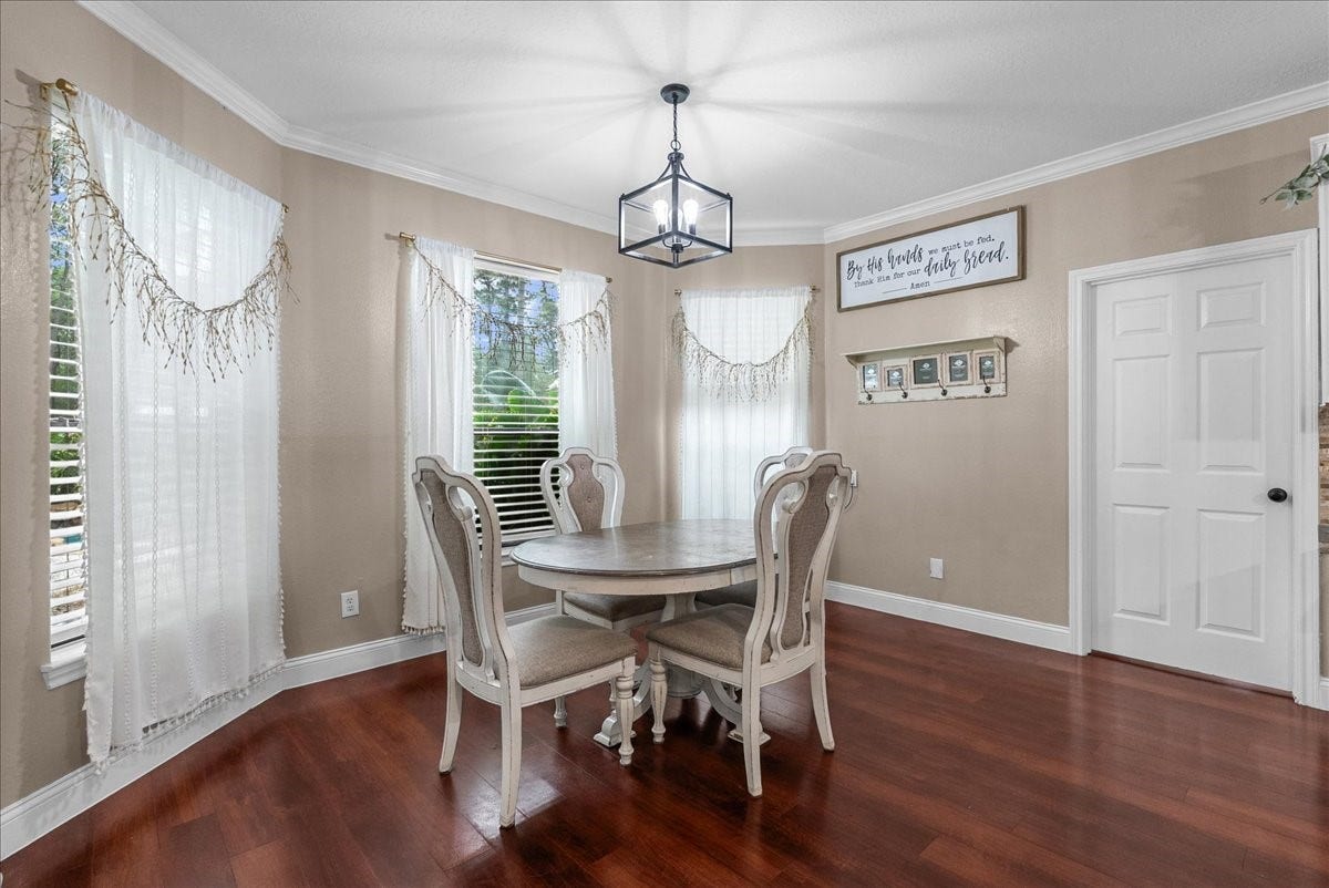 7202 Pine Drive W, Alvin, TX 77511 Charming dining area with elegant hardwood like floors, a stylish round table, and abundant natural light streaming through large windows adorned with sheer curtains.