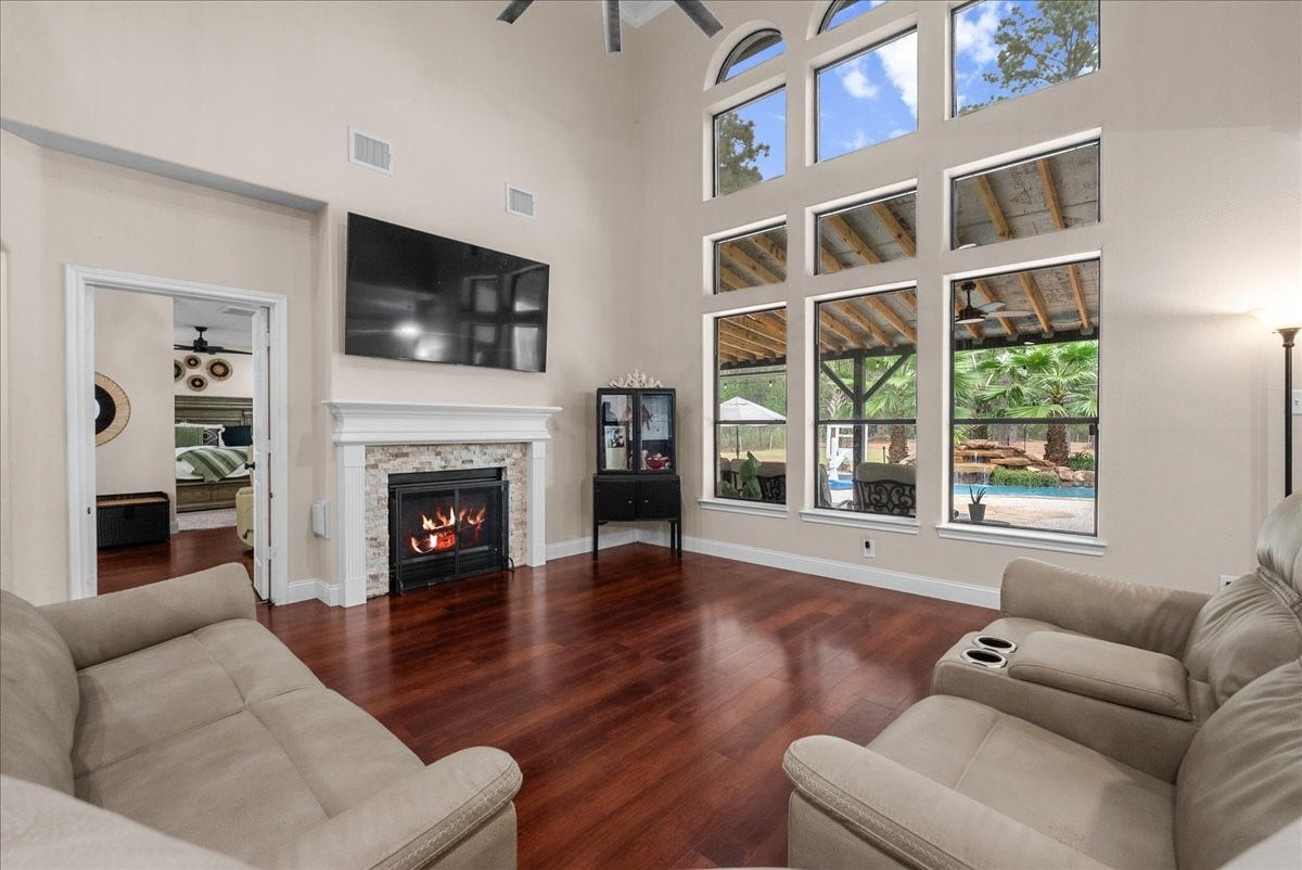 7202 Pine Drive W, Alvin, TX 77511 Elegant living room featuring soaring ceilings, a cozy fireplace, and expansive windows overlooking a scenic backyard oasis.