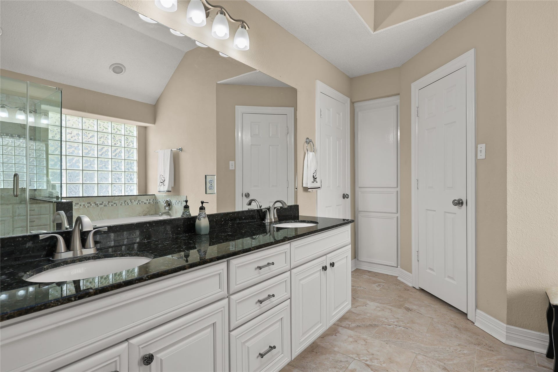 3424 Glastonbury Drive, Pearland, TX 77581 Elegant primary bathroom featuring a double vanity with sleek granite countertops, ample cabinet storage, and a spacious walk-in shower highlighted by stylish glass block accents.