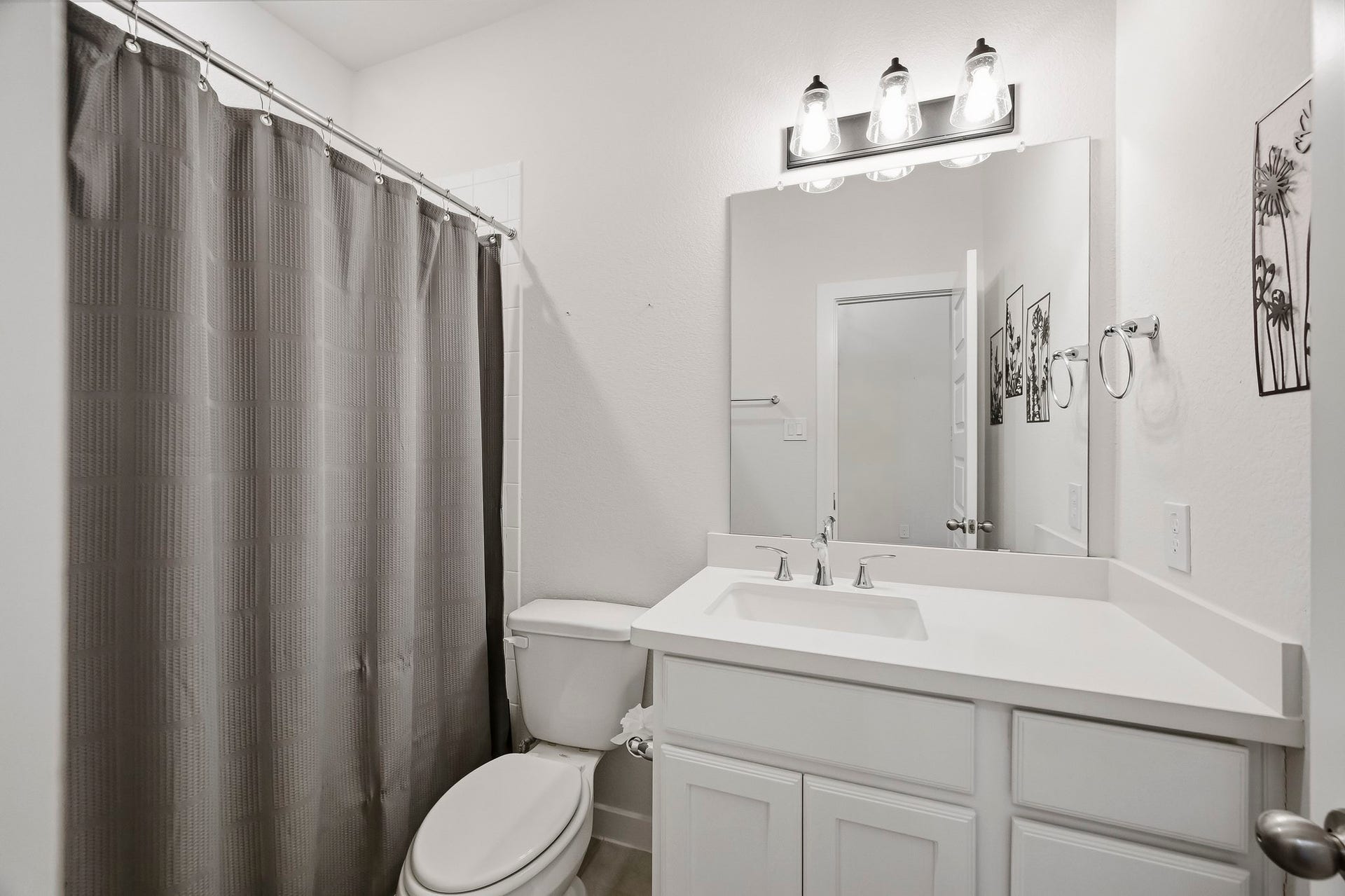 The downstairs full bathroom with quartz counters, a spacious tub and shower, and large vanity, is located just off the downstairs secondary bedroom, making it a perfect place for guests to unwind.