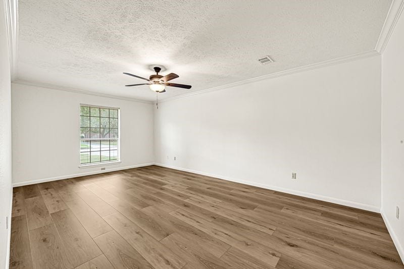 9907 Sagegreen Drive, Houston, TX 77089 Spacious room with elegant wood flooring, a large window for natural light, and a ceiling fan for comfort.