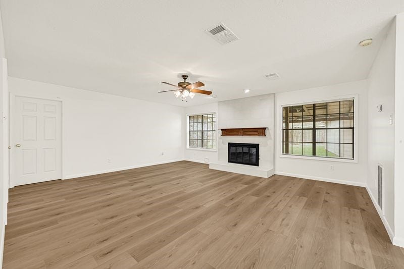 9907 Sagegreen Drive, Houston, TX 77089 Spacious living room with elegant wood flooring, a cozy fireplace, and large windows offering abundant natural light.