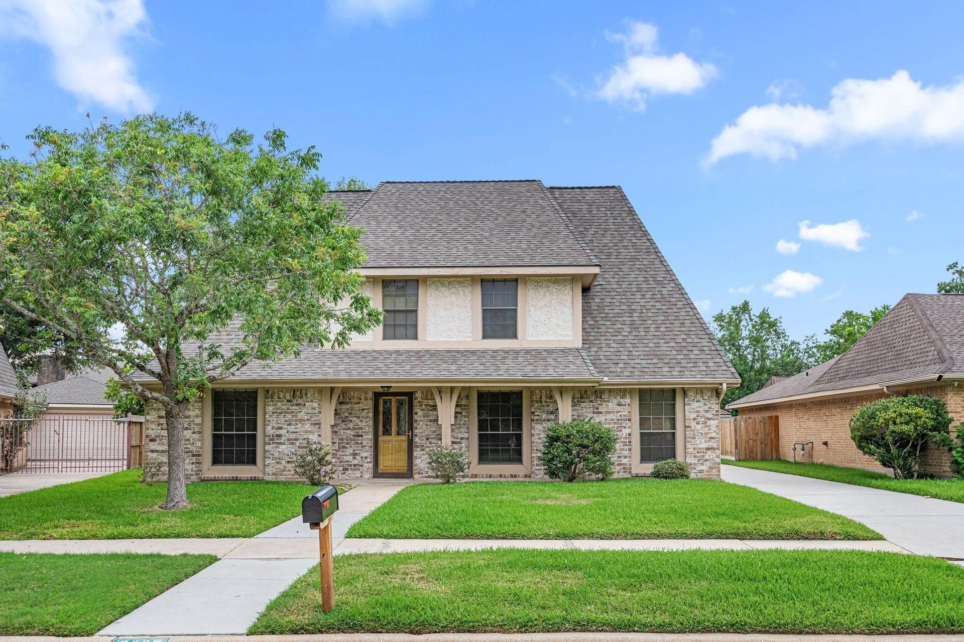9907 Sagegreen Drive, Houston, TX 77089 Charming two-story home with a classic brick facade, inviting covered porch, and a spacious front yard, perfect for family living.