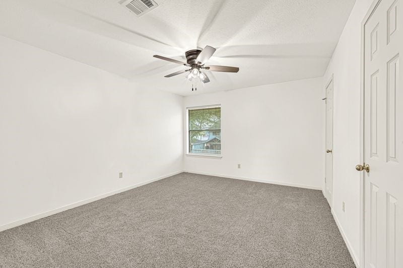 9907 Sagegreen Drive, Houston, TX 77089 Spacious bedroom featuring plush carpeting, a ceiling fan for comfort, and ample natural light from a large window.