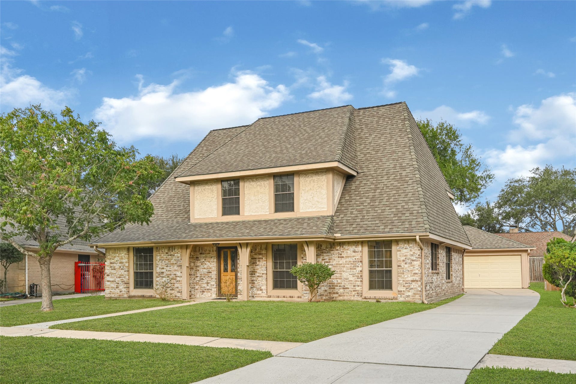 9907 Sagegreen Drive, Houston, TX 77089 Charming two-story brick home with a steeply pitched roof, spacious driveway, and well-maintained front lawn, offering a welcoming and picturesque curb appeal.