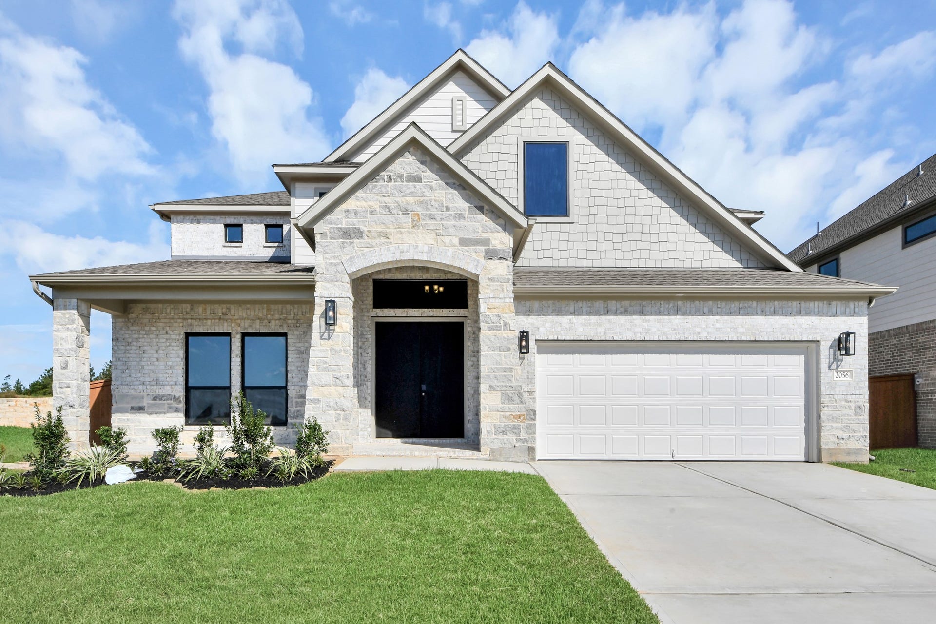 2056 Thimbleberry Lane, Magnolia, TX 77355 Meticulously maintained yard and lush landscape, paired with a premium elevation featuring captivating brick accents. Modern coach lights add a touch of contemporary elegance to the exterior.