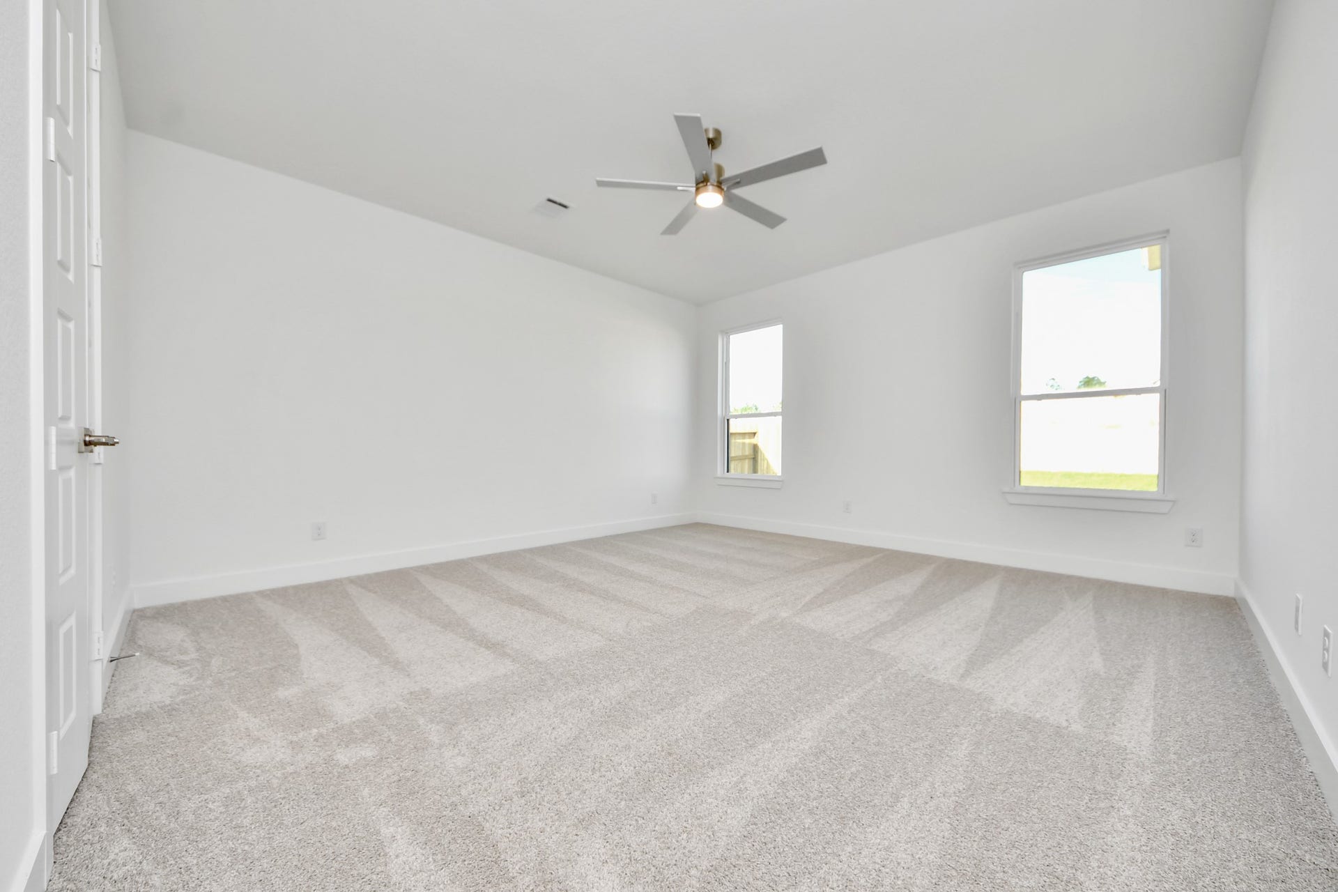 2056 Thimbleberry Lane, Magnolia, TX 77355 Retreat to the luxurious primary suite, your perfect escape for unwinding after a long day. Located on the first floor, this spacious room features plush carpeting, calming paint tones, high ceilings, and large windows with privacy blinds.