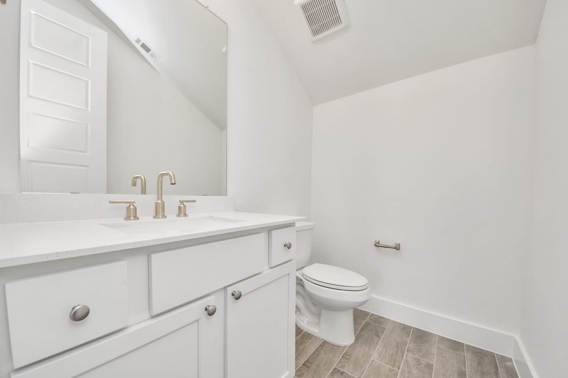 2056 Thimbleberry Lane, Magnolia, TX 77355 Sophisticated half bathroom adorned with contemporary finishes. The elegant 5-panel door welcomes you to a space where style meets functionality. Notice the sleek hardware accents that add a touch of modern charm. The vanity boasts light-colored countertops, beautifully complemented by a tasteful vanity light, creating a well-lit and inviting atmosphere.