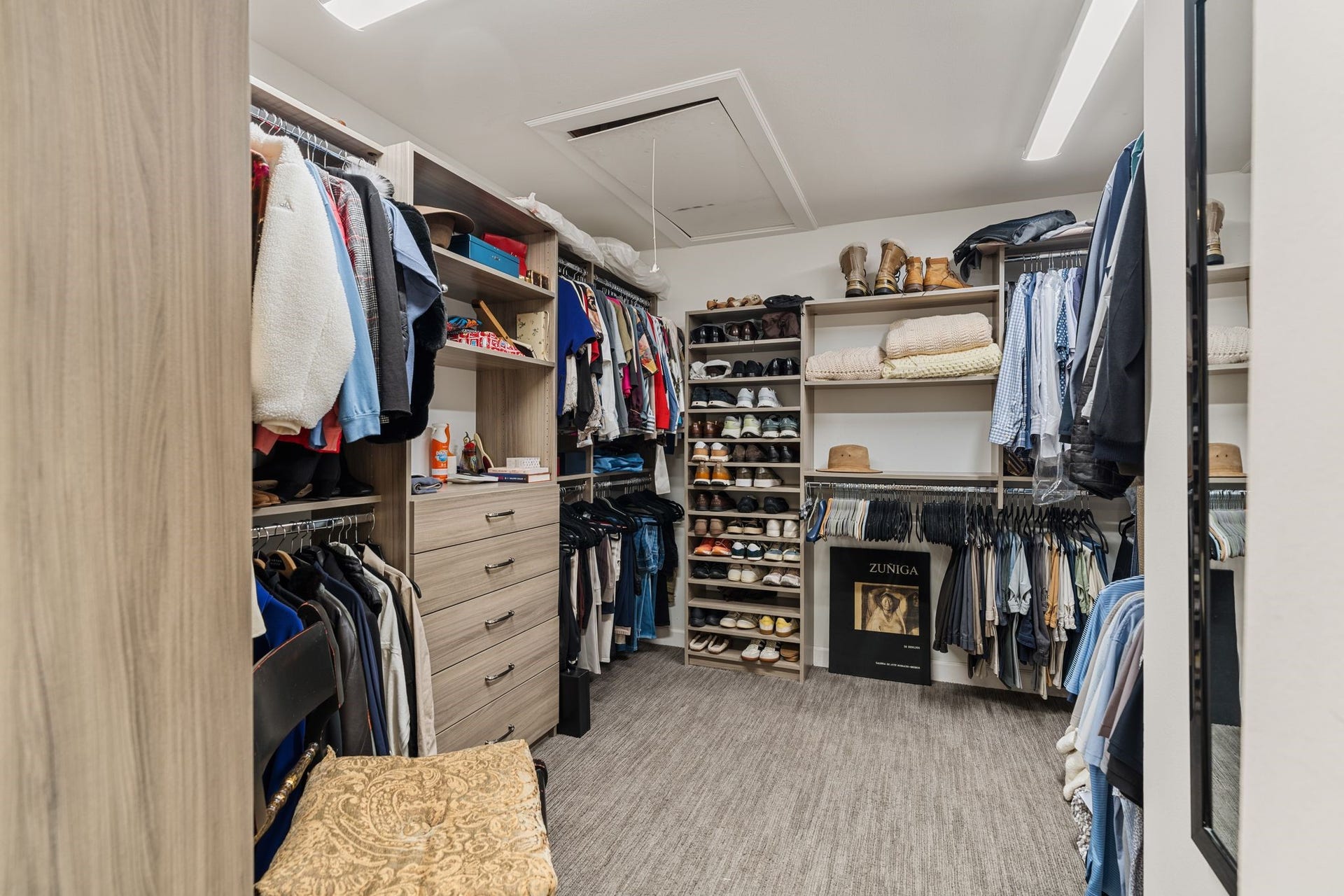 1918 Stoney Brook Drive, Houston, TX 77063 A spacious walk-in closet features built-in drawers, extensive shoe shelving and multiple hanging sections for organized wardrobe storage.