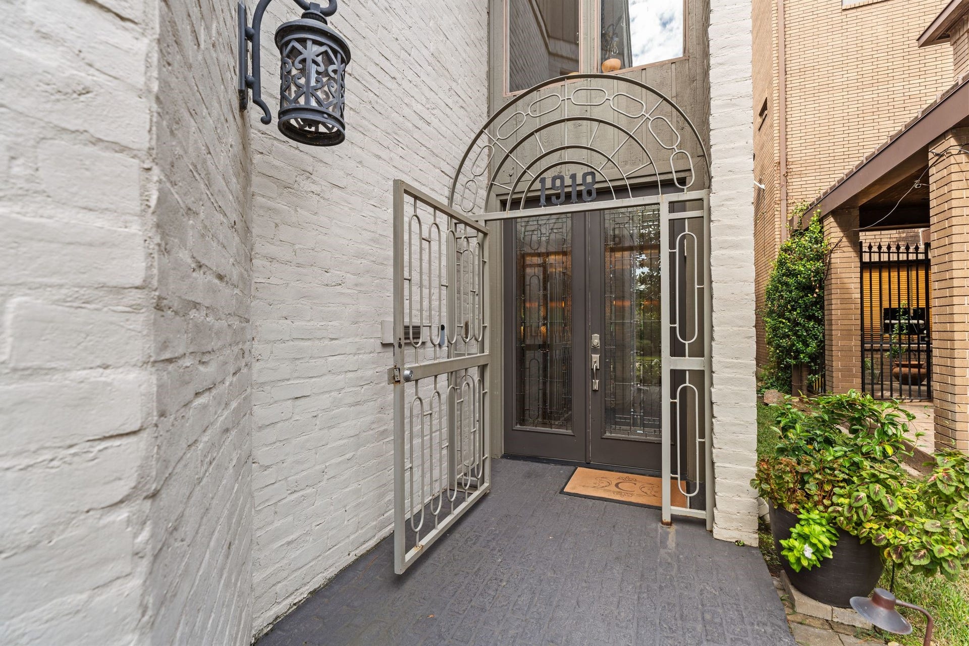 1918 Stoney Brook Drive, Houston, TX 77063 A decorative arched gate, glass double doors and lantern lighting create a distinctive entrance framed by painted brick.