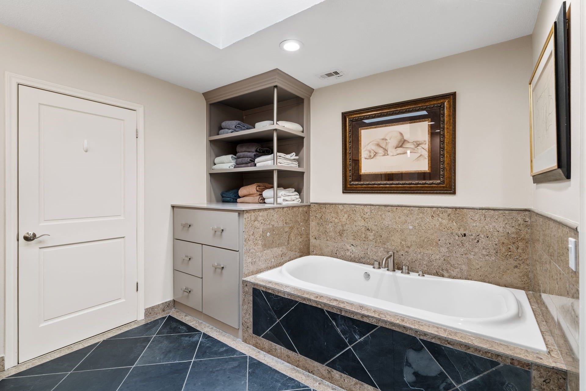 1918 Stoney Brook Drive, Houston, TX 77063 A separate soaking tub with a stone surround offers a relaxing retreat, complemented by built-in linen shelving and cabinetry.