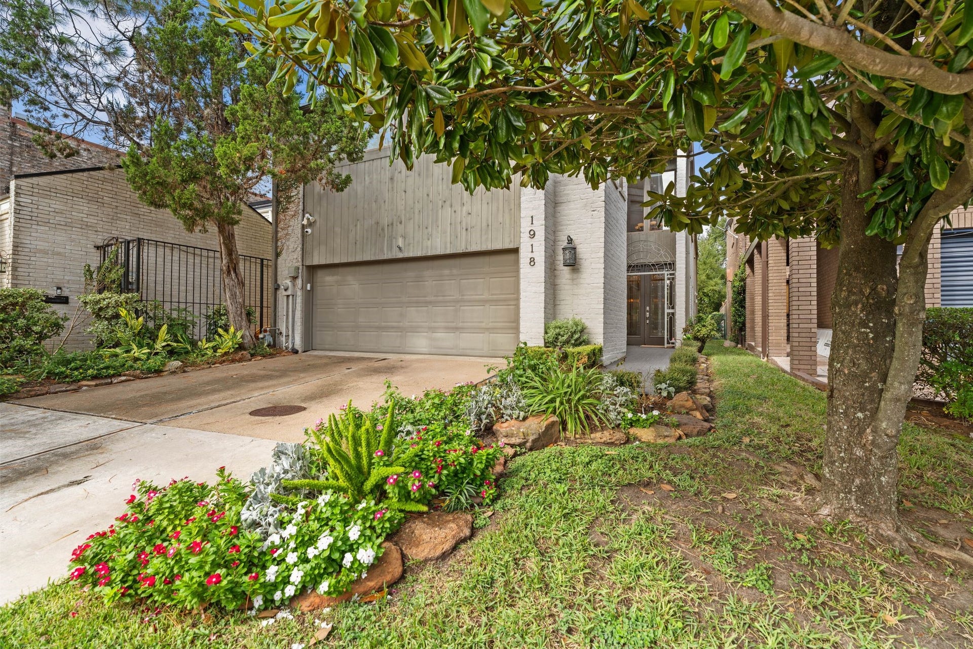 1918 Stoney Brook Drive, Houston, TX 77063 Colorful flower beds and established trees frame the front exterior, with a landscaped walkway leading to the recessed, gated entrance.