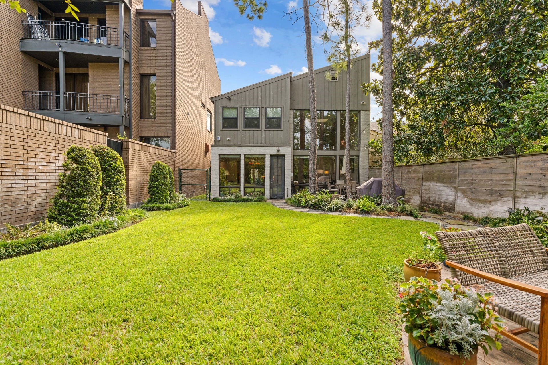1918 Stoney Brook Drive, Houston, TX 77063 Dramatic rear windows overlook a lush lawn framed by established landscaping and tall trees. Fenced outdoor area includes adjoining county-owned land.
