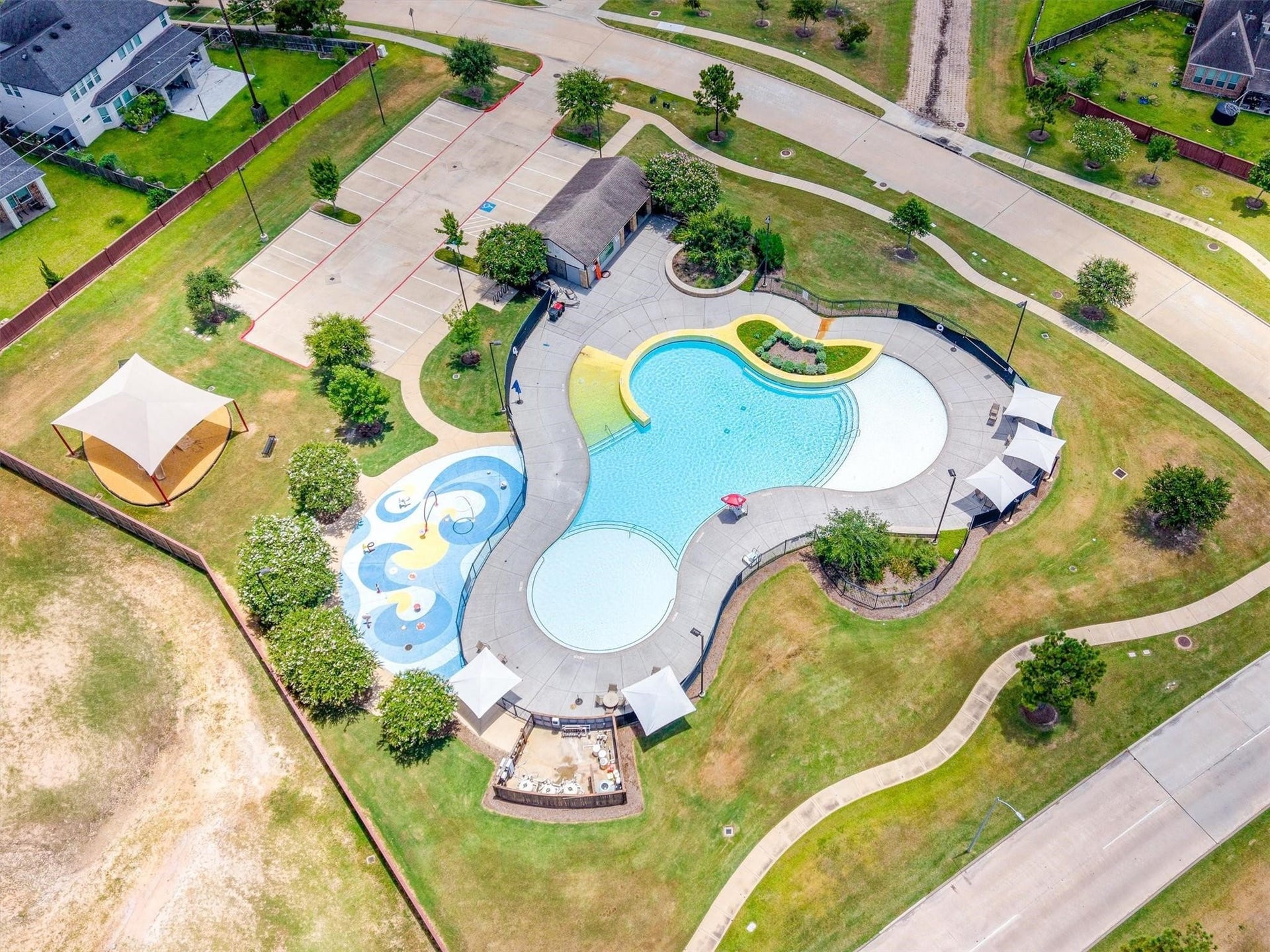 27022 Brighton Valley Way SW, Katy, TX 77494 Aerial view of the community's resort style pool, splash pad, shaded cabanas, and clubhouse with dedicated parking.
