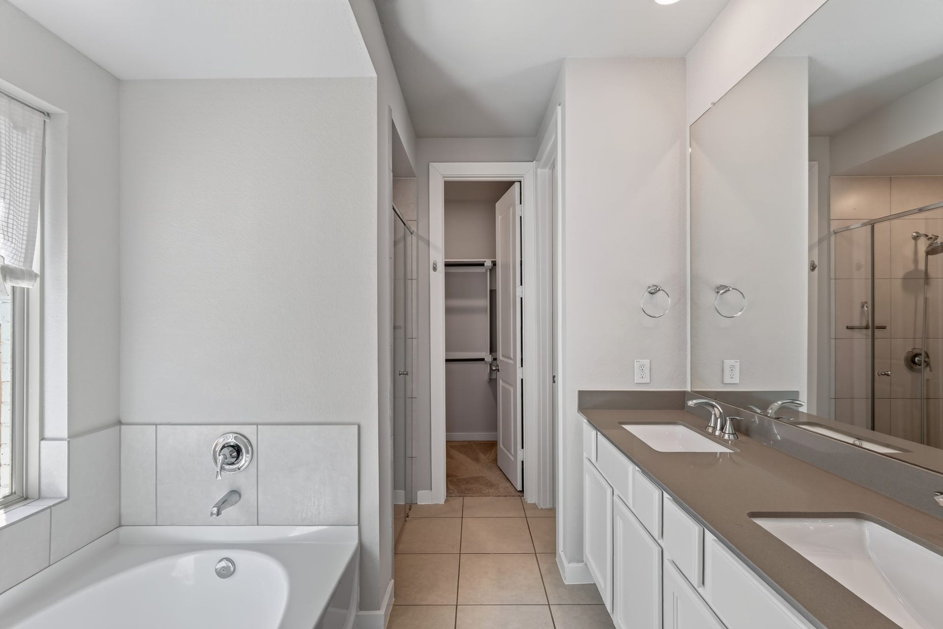 706 Santa Elena Trail, Conroe, TX 77304 The primary bathroom delivers a spa-inspired experience, with a luxurious soaking tub, a stylish double vanity featuring dark countertops and crisp white cabinetry, and elegant modern fixtures your personal retreat at the end of every long day.
