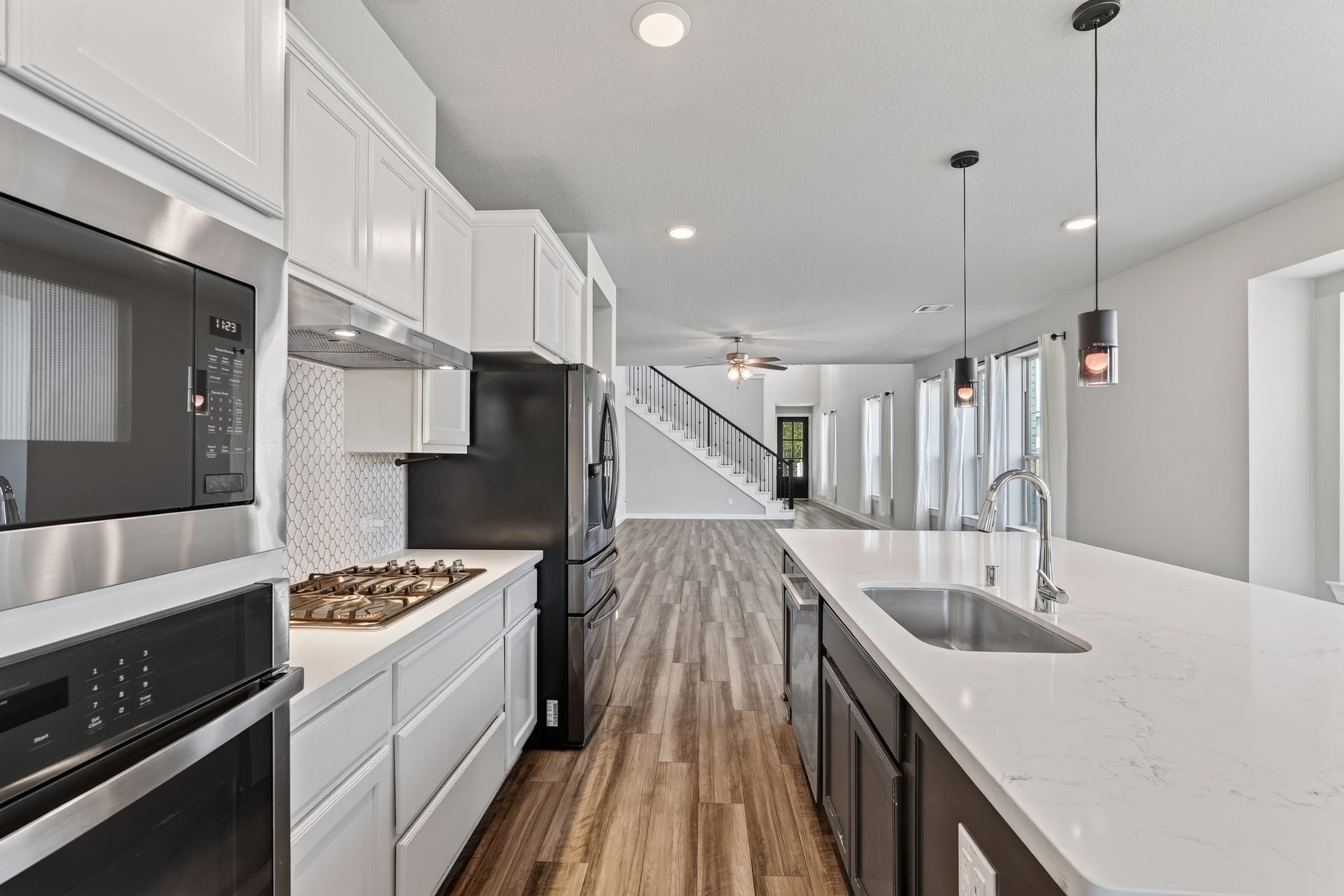 706 Santa Elena Trail, Conroe, TX 77304 The kitchen's gas range sits perfectly between white cabinetry and the striking navy blue island, flanked by warm pendant lighting above. Every element of this kitchen was carefully designed for both outstanding daily function and timeless stylish appeal.