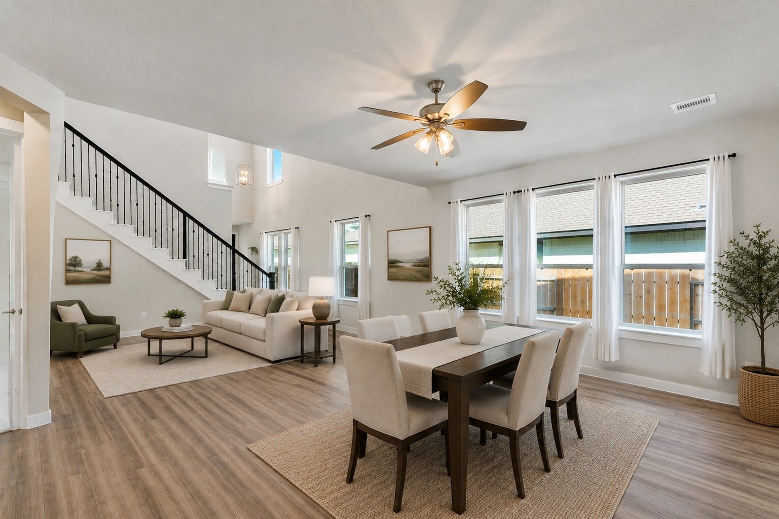 706 Santa Elena Trail, Conroe, TX 77304 Bright and welcoming family room with a ceiling fan, oversized windows that pour in natural light, and the home's beautiful iron stair railing as a backdrop. Dark hardwood-style flooring flows seamlessly throughout, tying all the downstairs spaces together.