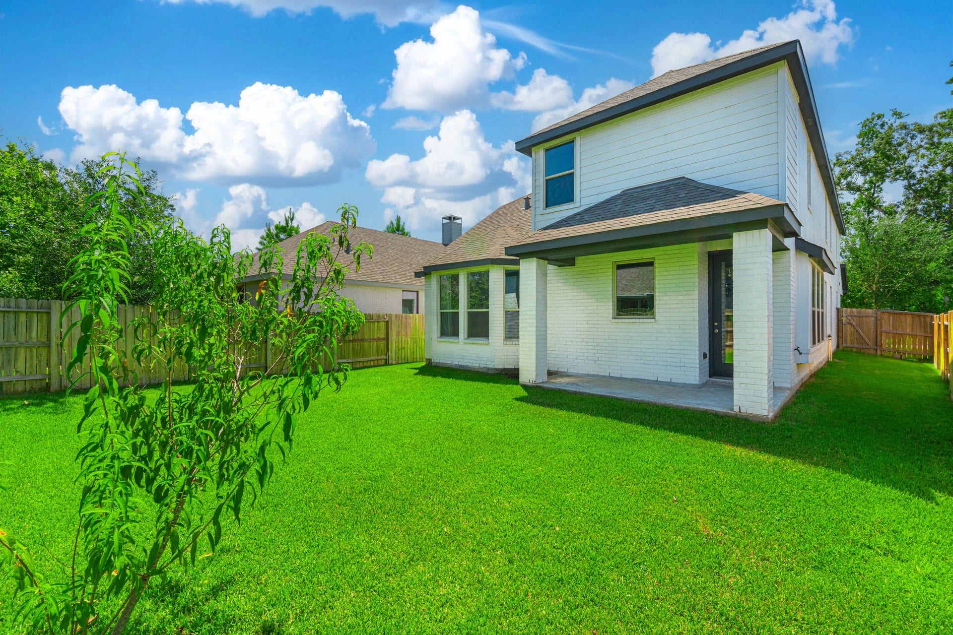 706 Santa Elena Trail, Conroe, TX 77304 The rear exterior of 706 Santa Elena Trail showcases modern board-and-batten siding, clean architectural lines, and a lush green backyard with ample space for outdoor living. Move-in ready inside and out this home is truly the complete package.