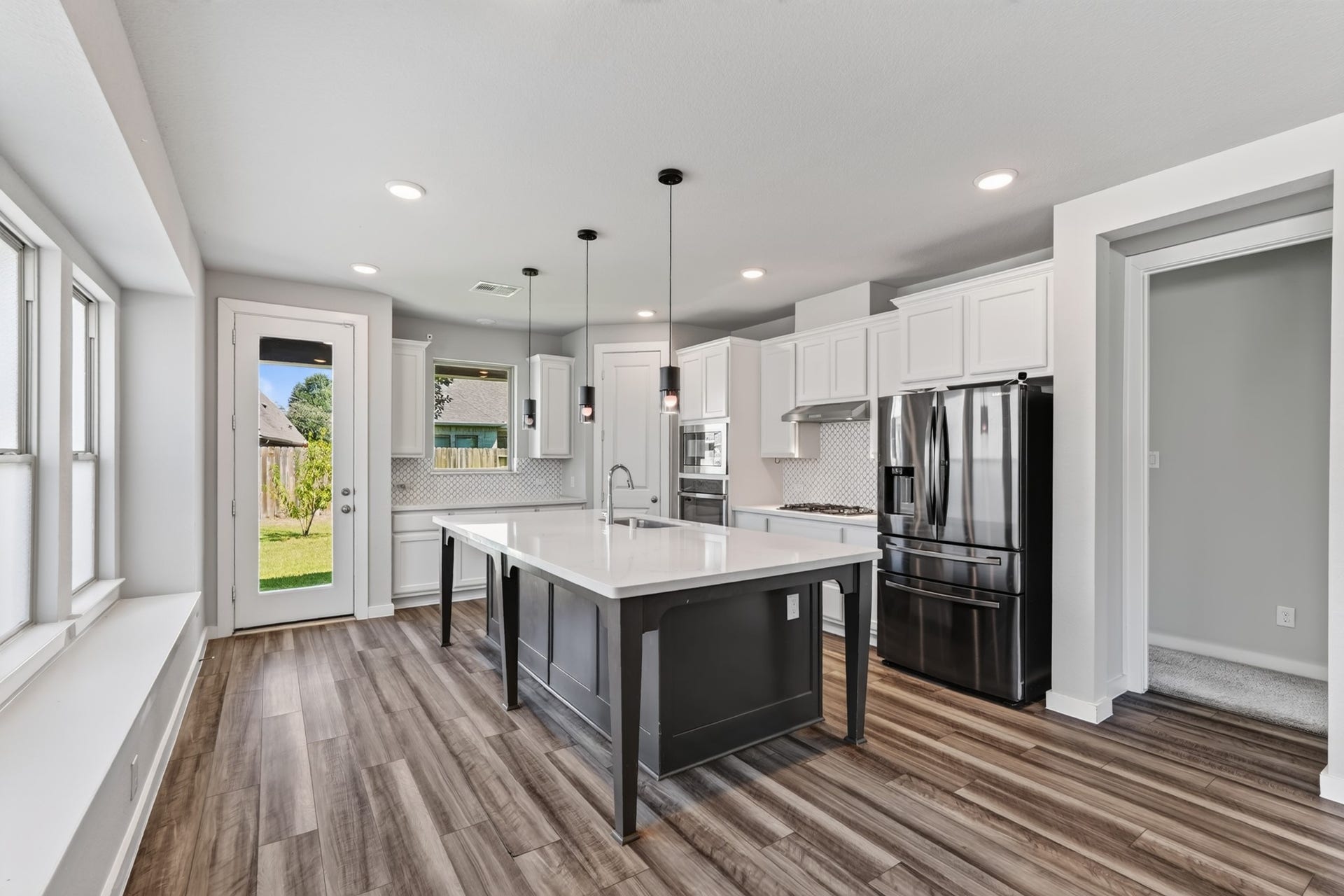 706 Santa Elena Trail, Conroe, TX 77304 A breathtaking kitchen opens directly to the family and dining areas featuring crisp white cabinetry, a bold navy blue island with quartz countertops, pendant lighting, and stainless steel appliances. This kitchen was designed to impress every single day.