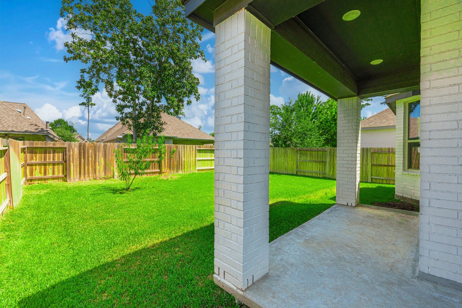 706 Santa Elena Trail, Conroe, TX 77304 The covered back patio is your private outdoor retreat white columns, a generous concrete pad, and a shaded overhead structure invite you to enjoy morning coffee, evening meals, and weekend gatherings just steps from the kitchen in total comfort.