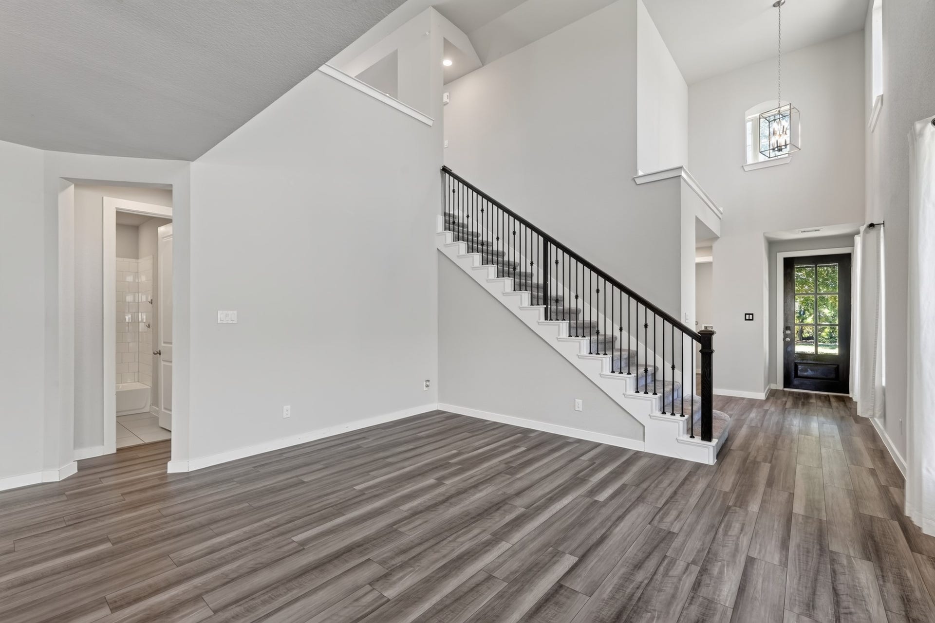 706 Santa Elena Trail, Conroe, TX 77304 The grand staircase is a true architectural highlight featuring elegant black iron balusters, crisp painted risers, and rich dark hardwood flooring at the base. A sophisticated design detail that elevates the character and quality of the entire main floor.