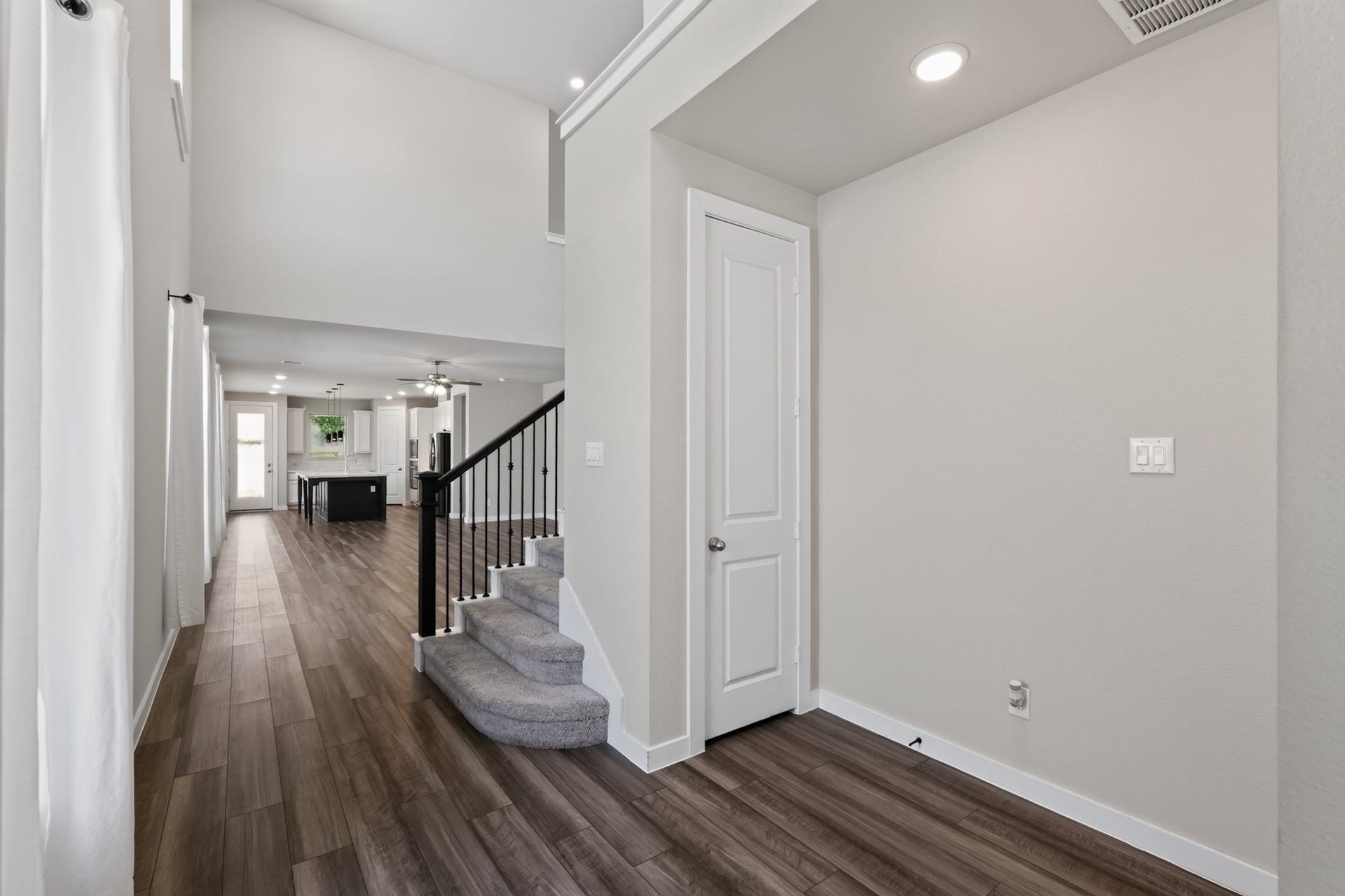 706 Santa Elena Trail, Conroe, TX 77304 Step inside to a bright, open entry foyer featuring gorgeous dark hardwood-style flooring, soaring ceilings, and crisp neutral walls. The staircase visible in the background adds immediate architectural elegance to this light-filled and spacious entryway.