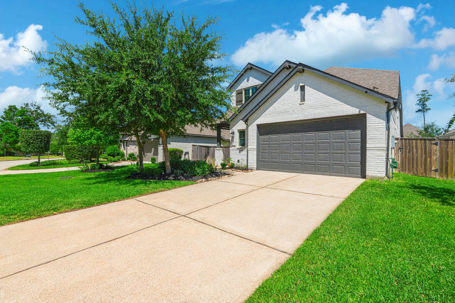 706 Santa Elena Trail, Conroe, TX 77304 Another look at this home's beautiful front elevation, highlighting the clean modern lines, stone accent details, manicured front lawn, and wide two-car garage. Grand Central Park's tree-lined streets make every arrival feel like coming home.
