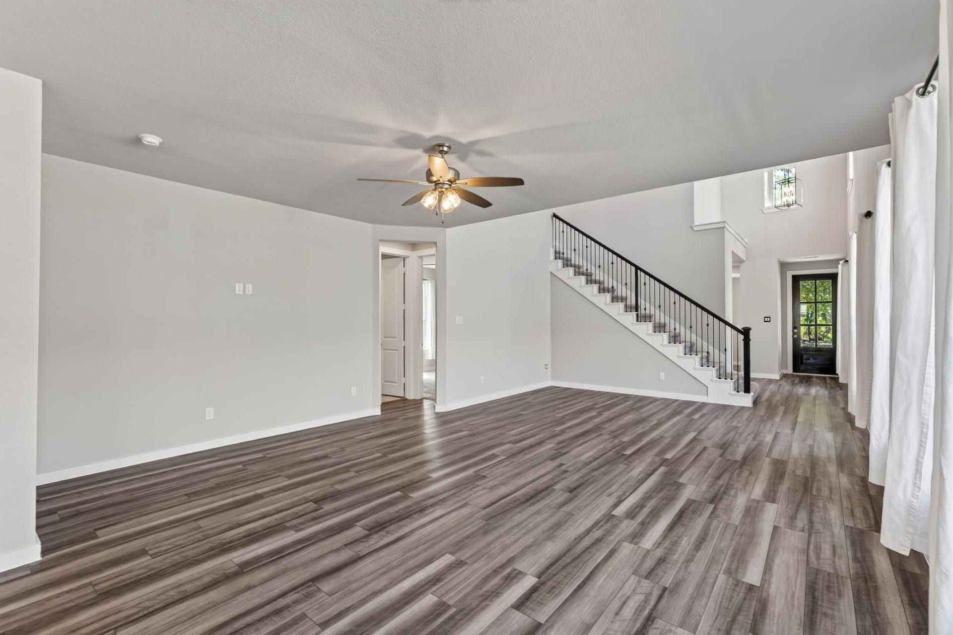 706 Santa Elena Trail, Conroe, TX 77304 The family room's open-concept design allows beautiful sight lines across the living, dining, and kitchen areas, with the elegant black iron stair railing adding striking visual interest. Dark hardwood floors and a ceiling fan complete the polished look.