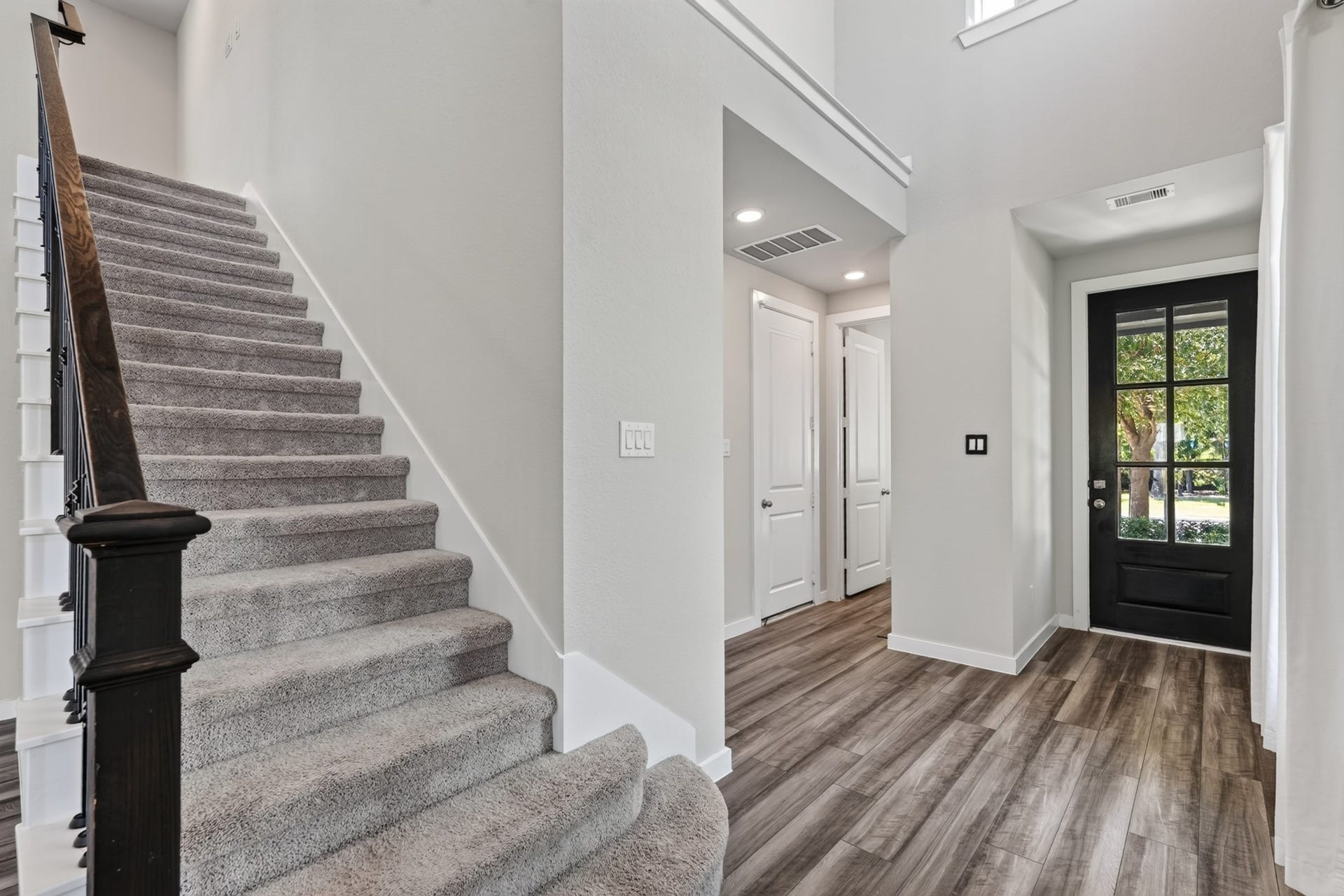 706 Santa Elena Trail, Conroe, TX 77304 A view toward the graceful staircase from the main floor puts the beauty of the black iron balusters and the craftsmanship of this design detail on full display. Together, the staircase and entry set a tone of quality and elegance throughout the entire home.