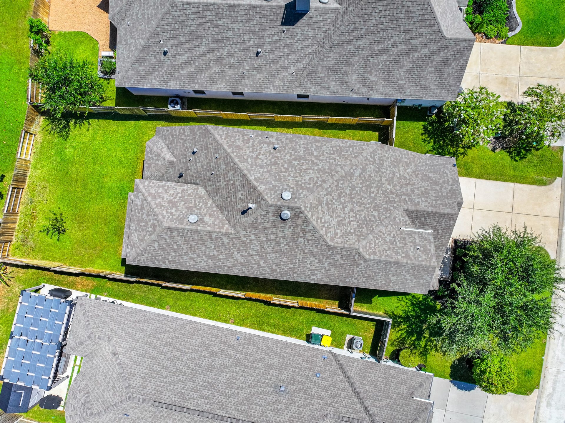 706 Santa Elena Trail, Conroe, TX 77304 Aerial view of 706 Santa Elena Trail shows the home's roofline, two-car garage, backyard, and beautiful surroundings within Grand Central Park. The neighborhood's green canopy, winding streets, and thoughtful master-planned community design are clearly visible.