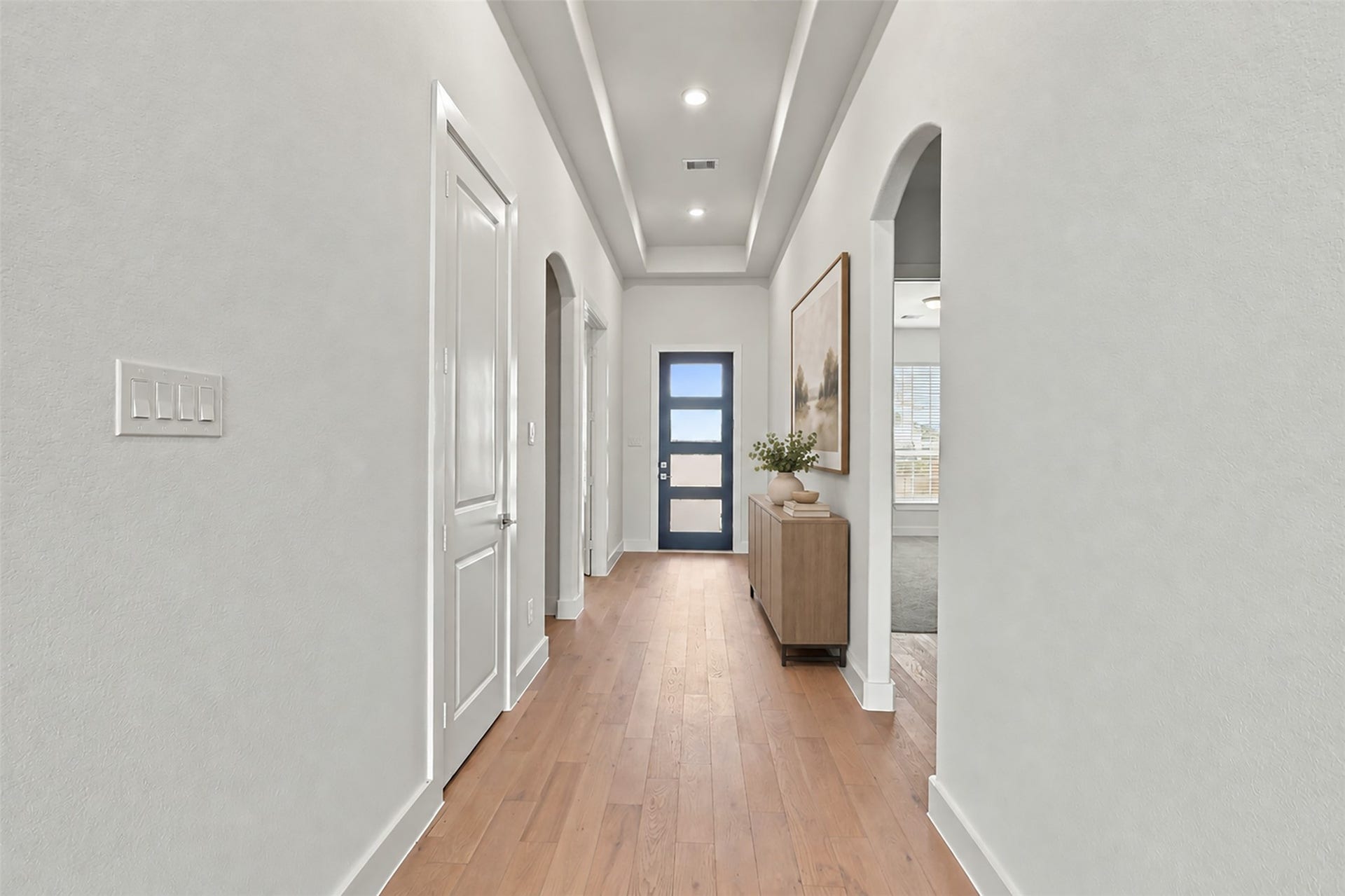1051 Lakeland Circle, Rosharon, TX 77583 A BEAUTIFUL WELCOME HOME! Gorgeous engineered wood flooring extends throughout this inviting hallway, creating a warm, cohesive look! Soft neutral walls, recessed lighting, and elegant ceiling details enhance the bright, open atmosphere! The arched architectural detail adds a touch of character as you make your way through this THOUGHTFULLY DESIGNED home! **Photo is Virtually Staged**